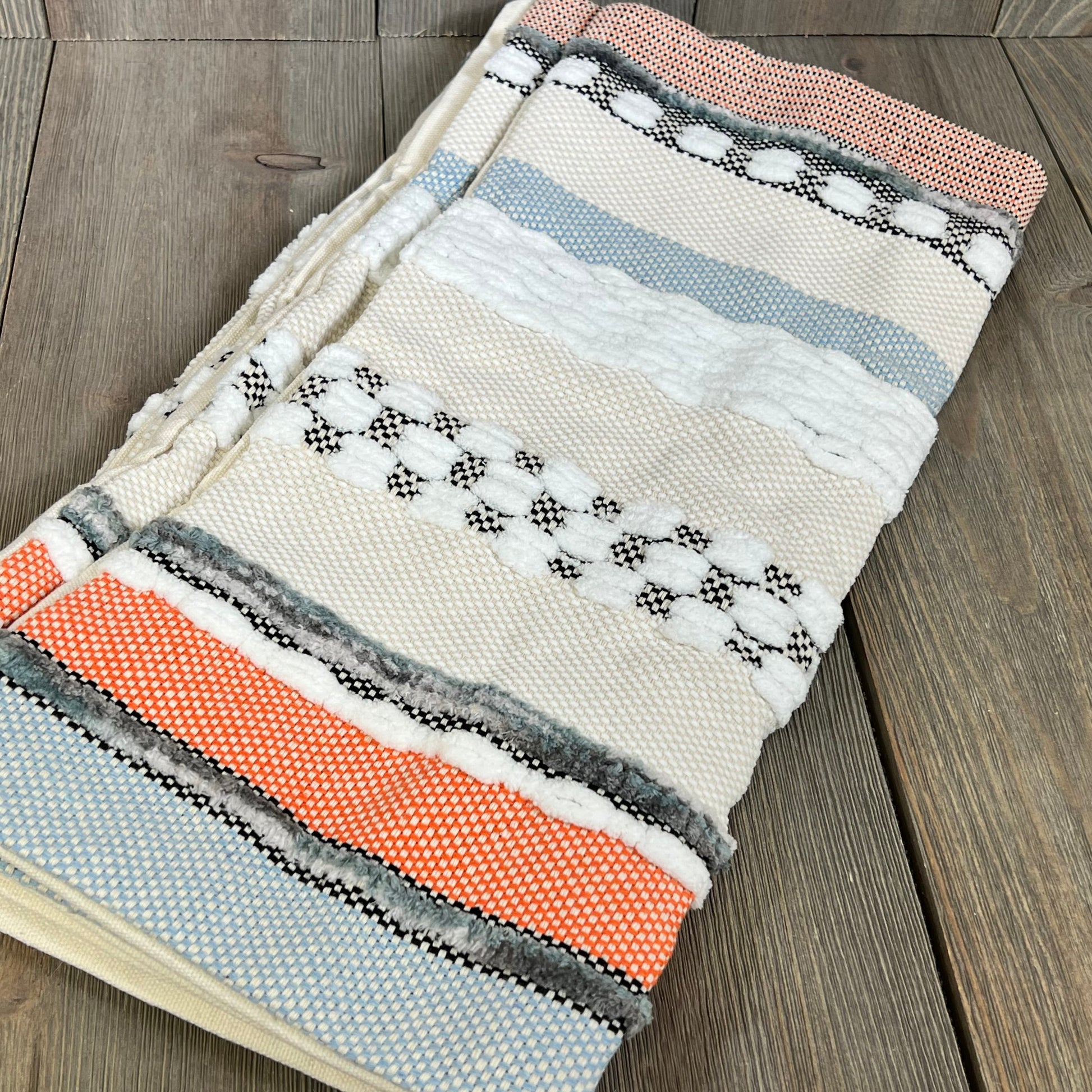 Boho throw pillow covers with orange and blue stripes, showcasing textured chenille design on a wooden surface.
