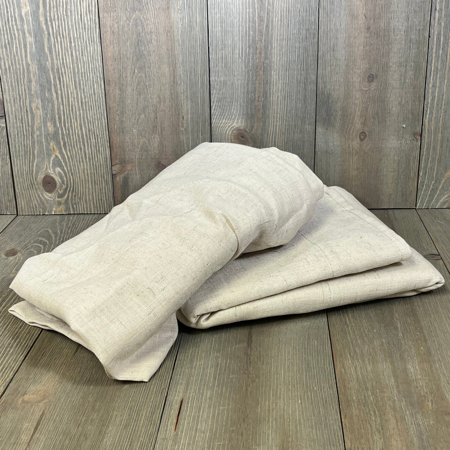 Folded H.VERSAILTEX linen curtains on wooden floor, showcasing soft, thick fabric in neutral tones, perfect for farmhouse decor.
