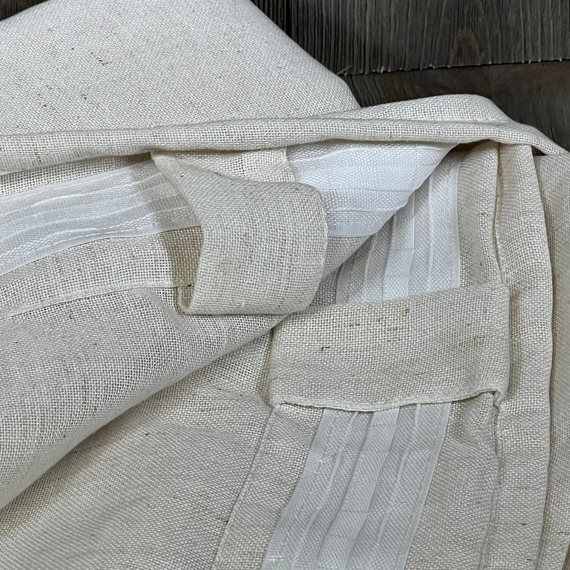 Cream linen drapes with back tab design, showcasing texture and craftsmanship, perfect for living room or bedroom decor.