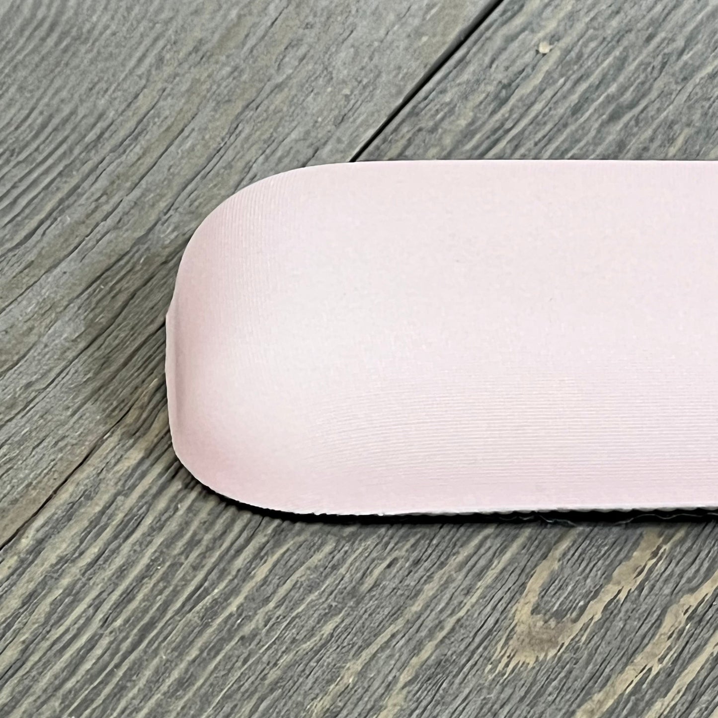 Ergonomic apricot wrist rest on wooden surface, featuring a curved memory foam design for comfort and pain relief.