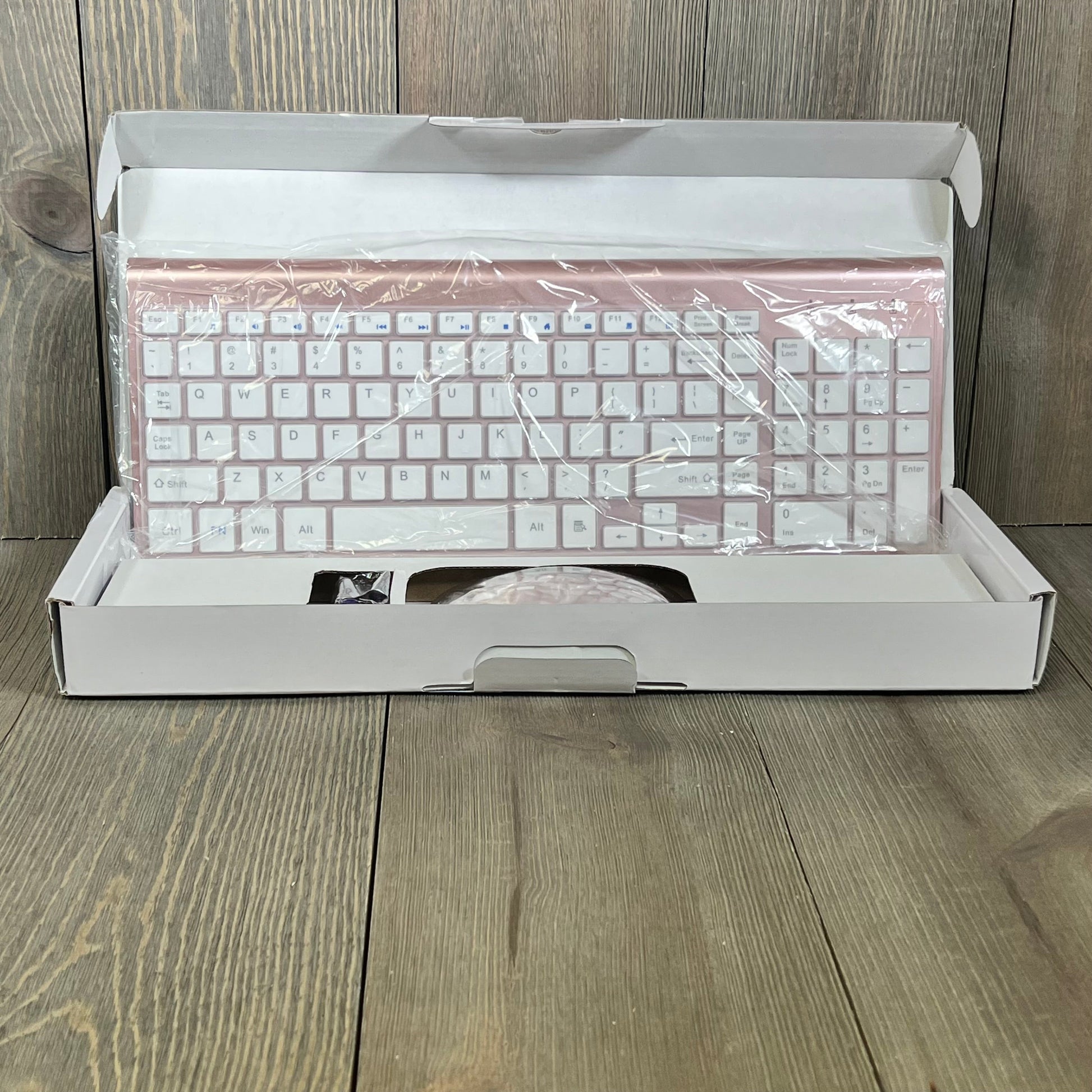 Rose gold wireless keyboard and mouse combo in open box, showcasing sleek design and compact layout for PC and Mac.