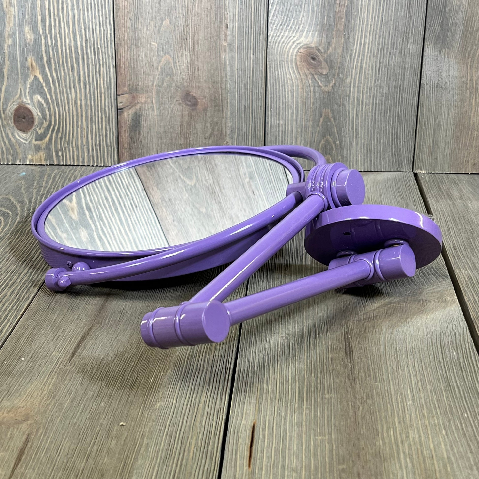 Lavender wall-mounted mirror with extending arm and twist accent, offering 4X magnification. Ideal for makeup application.