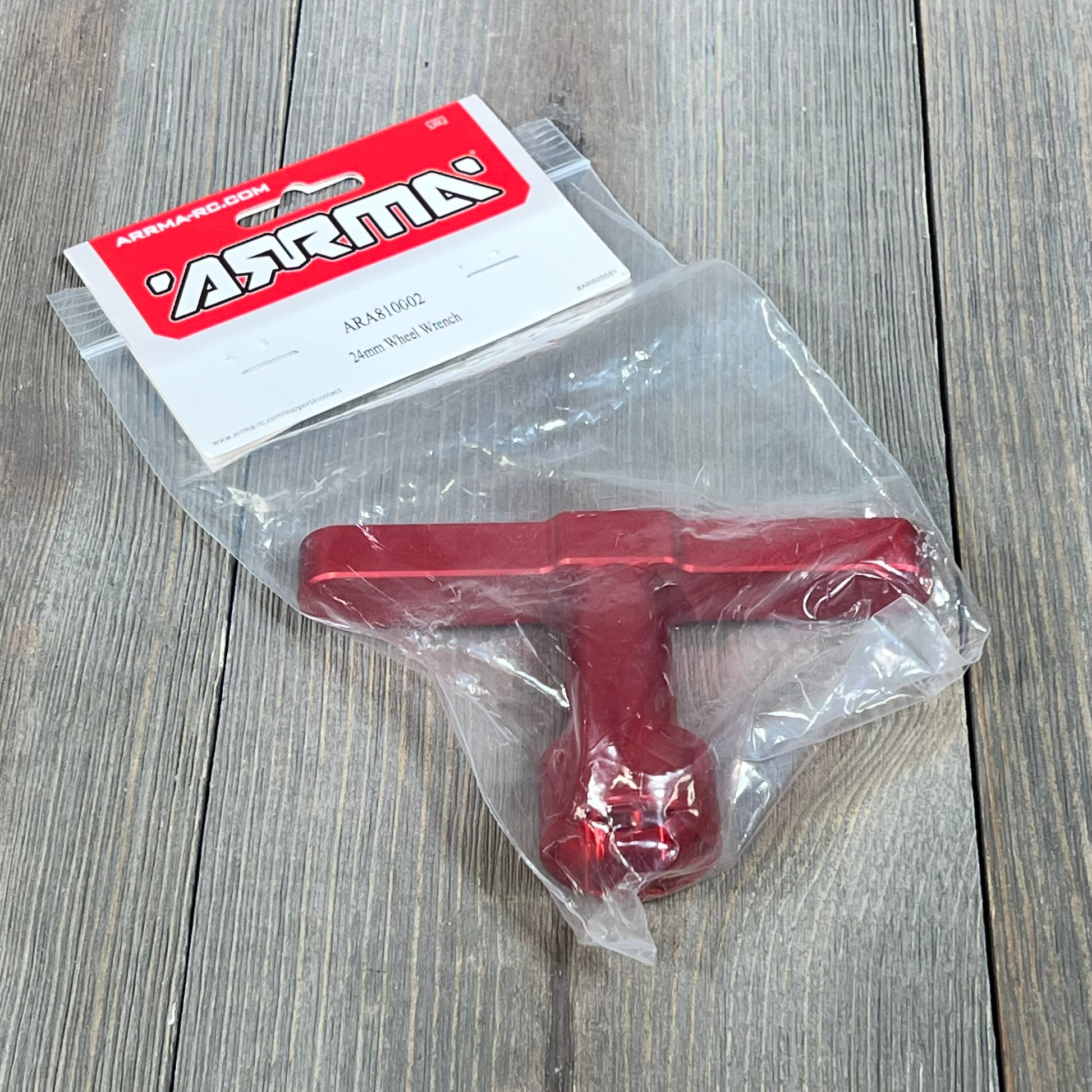 Red ARRMA 24mm Wheel Wrench ARA810002 in packaging on wooden surface, ideal for RC car maintenance.