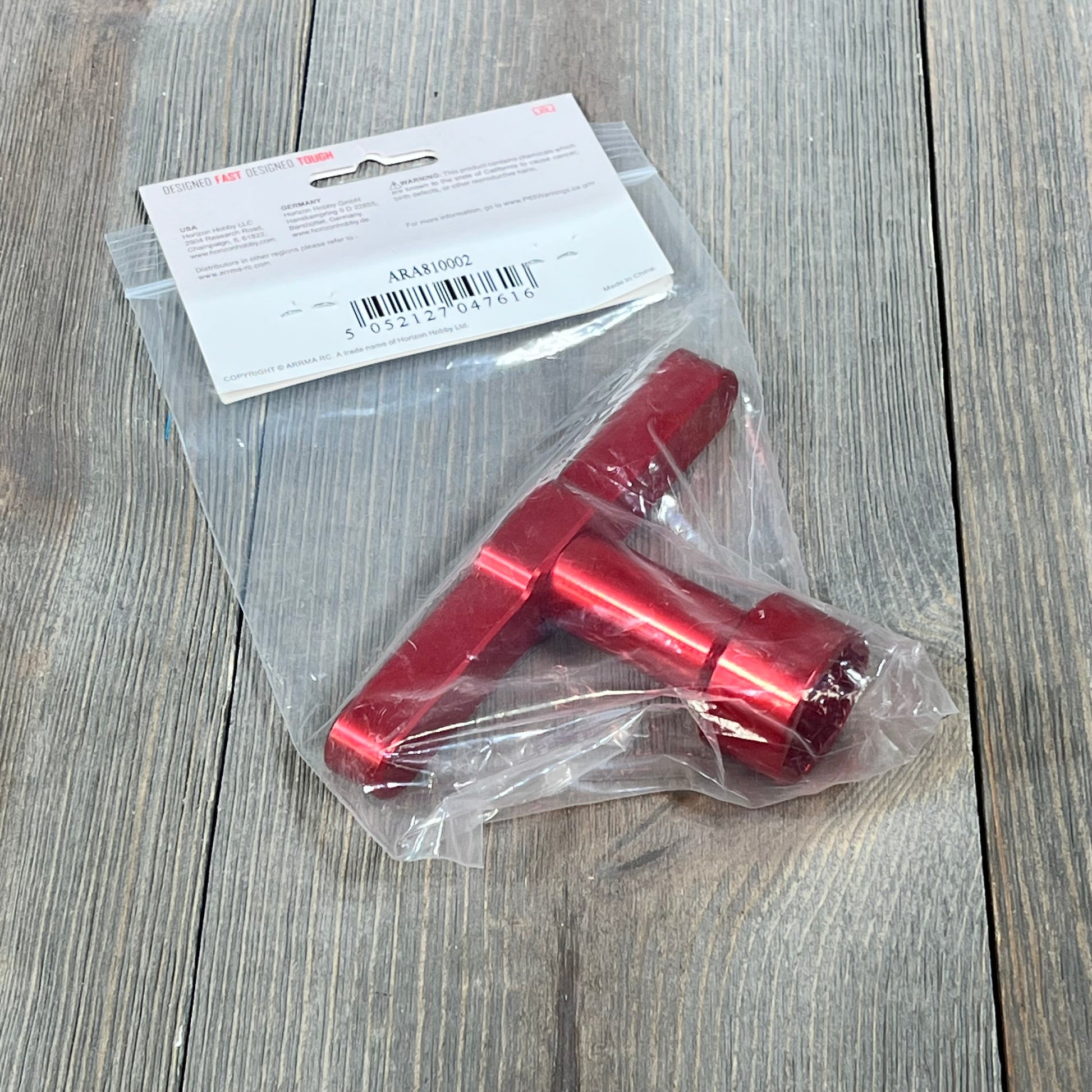 Red ARRMA 24mm wheel wrench ARA810002 in packaging on wooden surface, ideal for RC car maintenance.