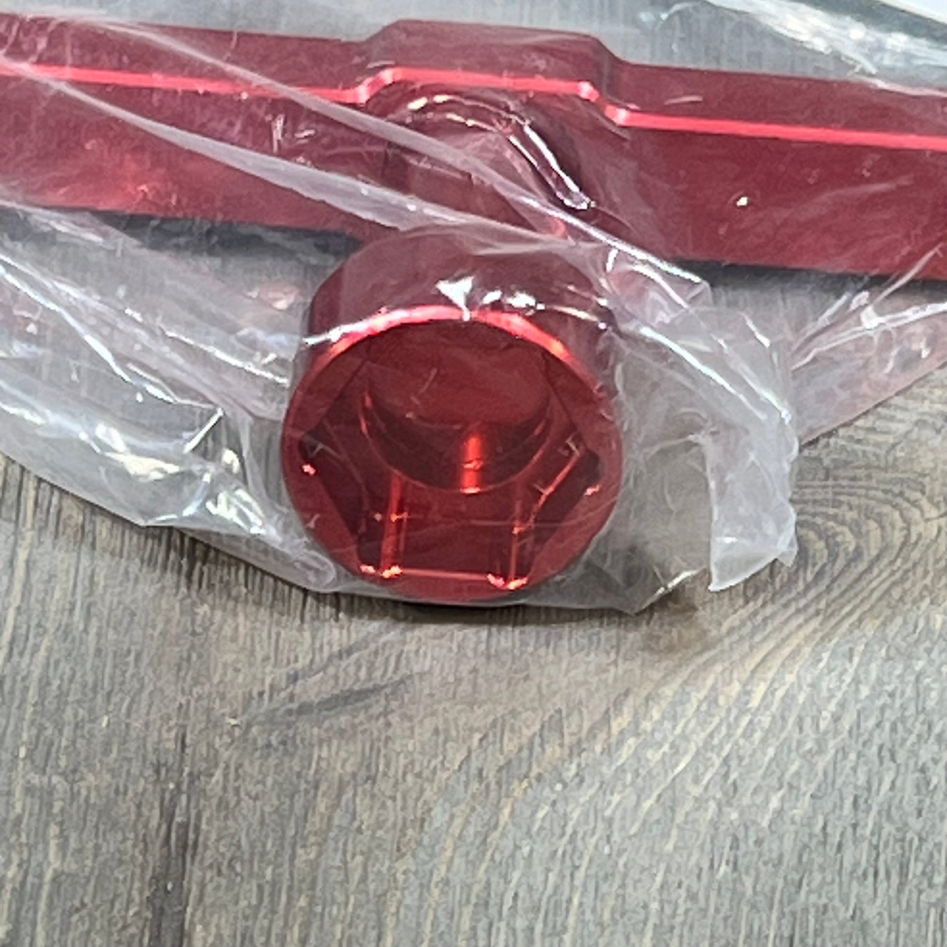 Red ARRMA 24mm wheel wrench ARA810002 in plastic wrap on a wooden surface, showcasing durable construction.