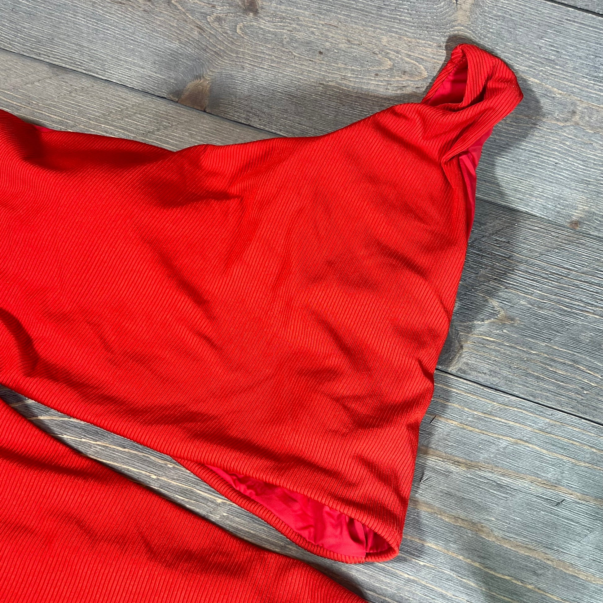 Red ribbed one-shoulder swimsuit with cutout detail, XL size, displayed on a wooden background.