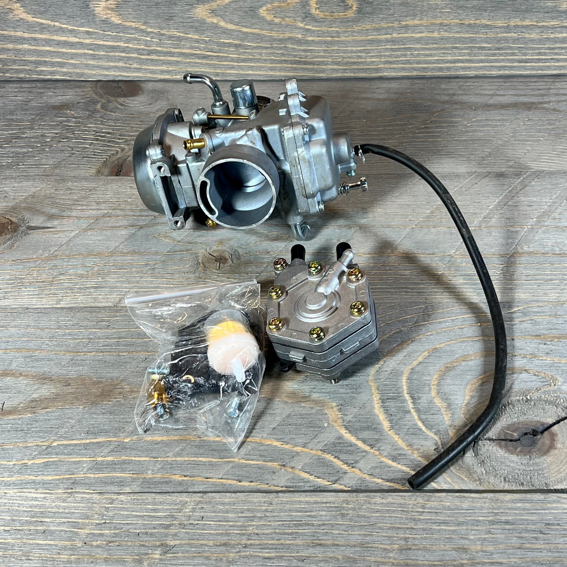 Replacement carburetor for Polaris Sportsman 500, showing detailed components on a wooden surface.