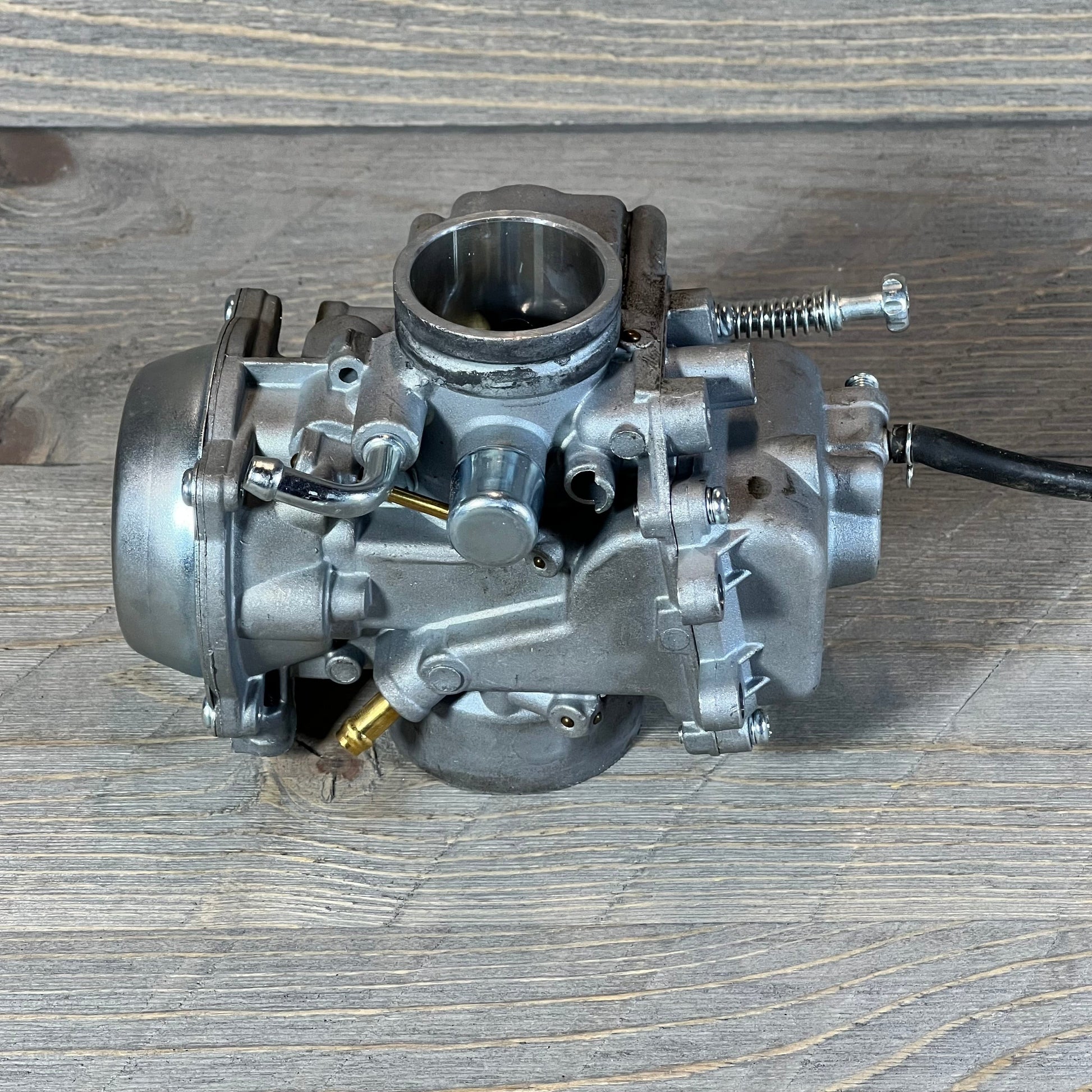Replacement carburetor for Polaris Sportsman 500, years 1996-1998, on wooden surface. Durable metal construction.
