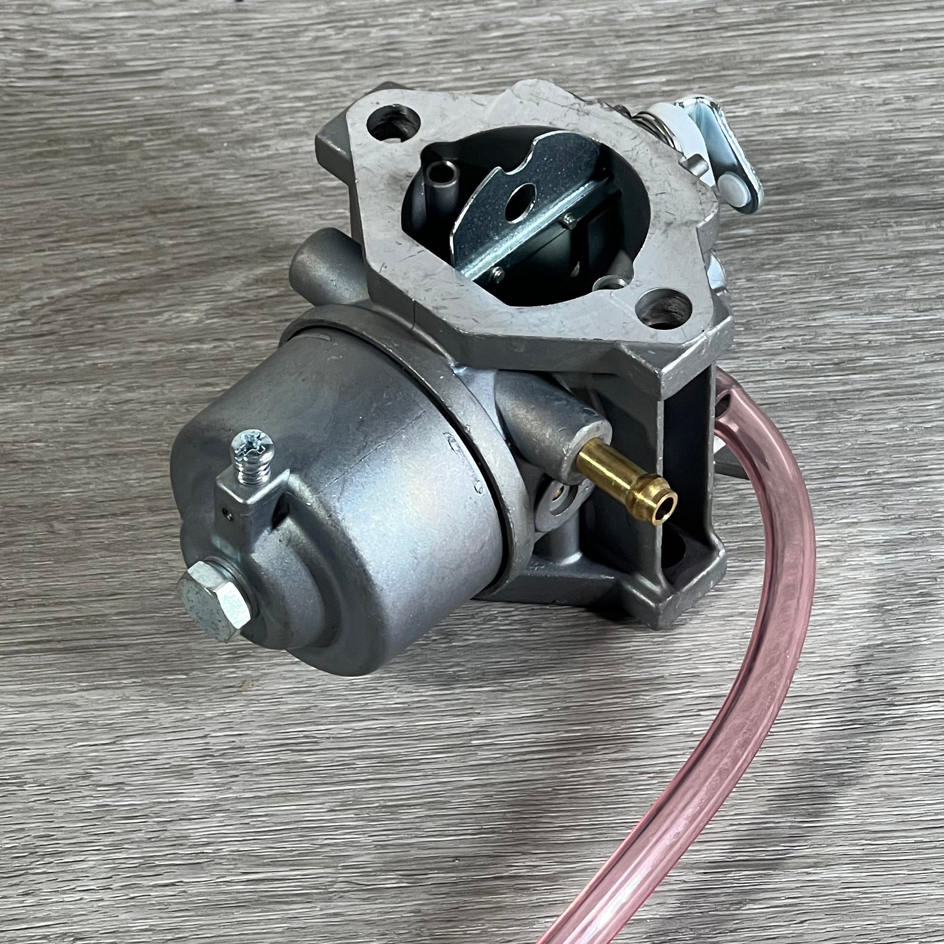 Replacement Cylinman carburetor for John Deere mowers, showcasing metal construction and fuel line attachment.