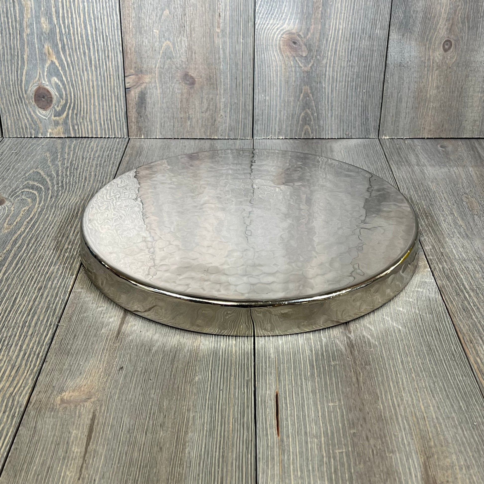 Hammered silver serving tray, 11-inch round, ideal for candles, jewelry, or food display on a wooden surface.