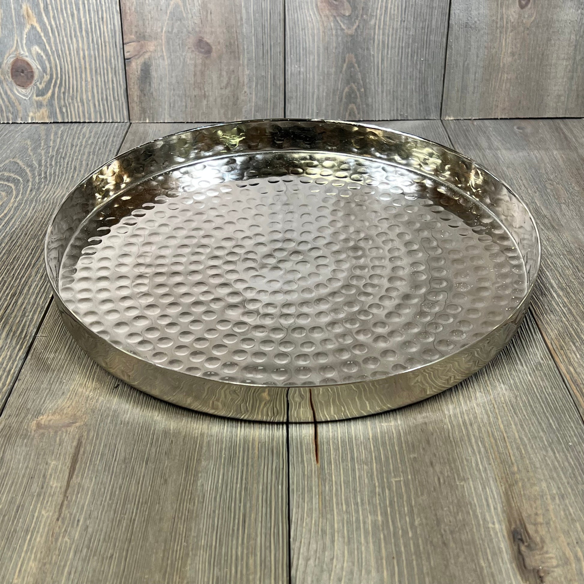 Hammered silver round serving tray, ideal for displaying candles, jewelry, or food on a coffee table, 11-inch diameter.