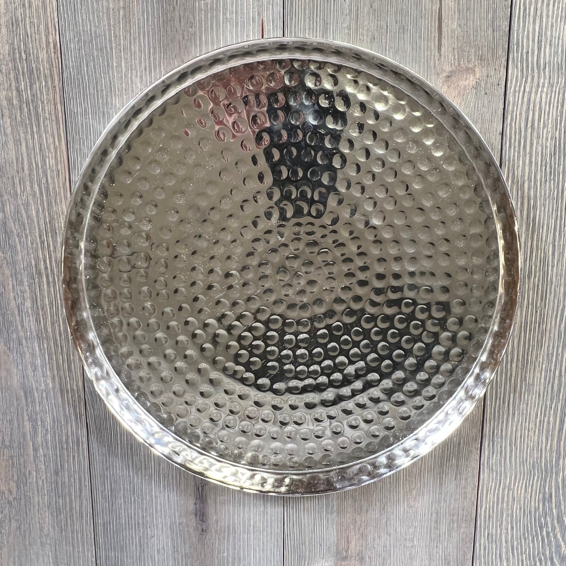 Hammered silver serving tray on wooden table, perfect for candles, jewelry, or food display.