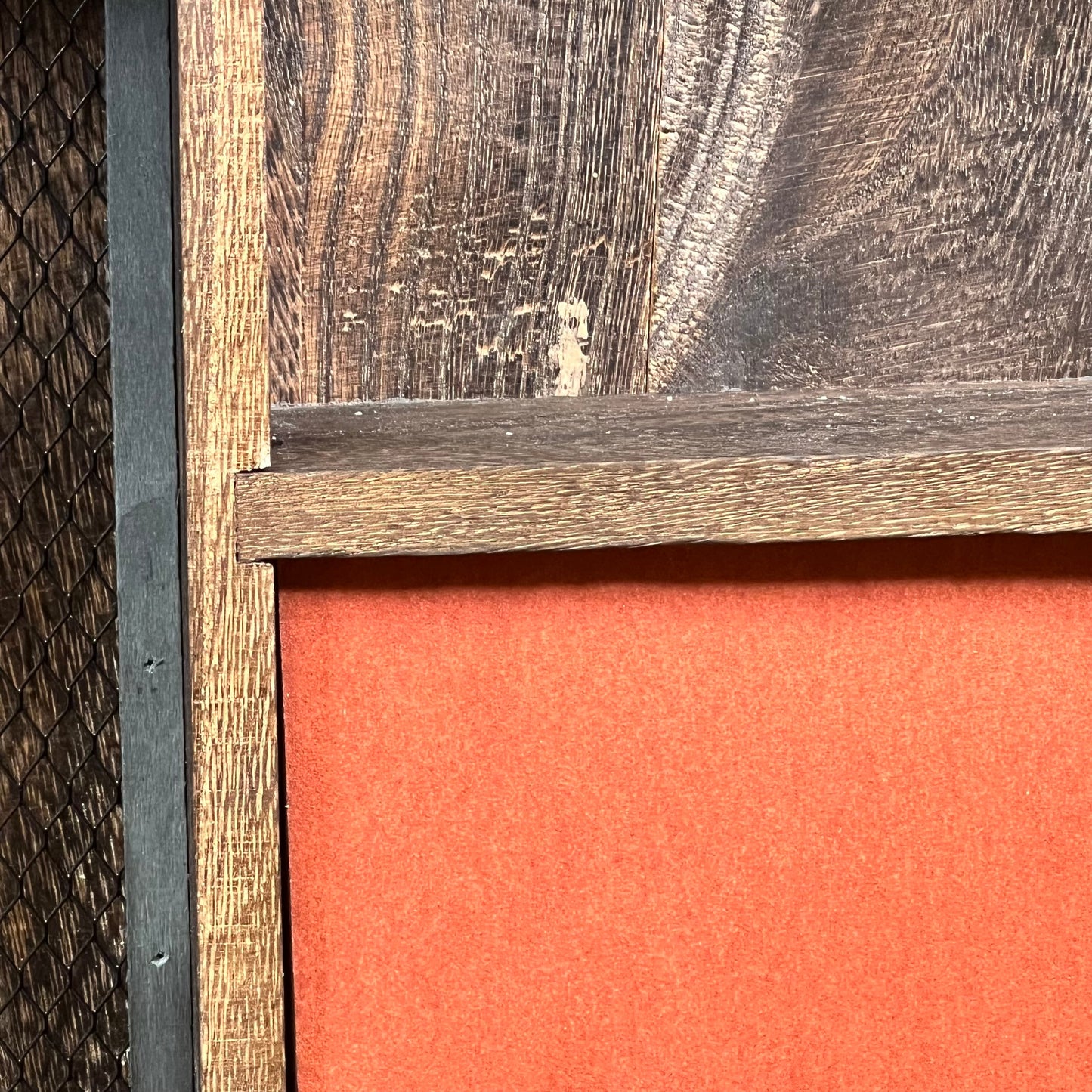 Close-up of rustic wooden texture on GLANT barn door jewelry organizer with vibrant orange interior for earrings and necklaces.