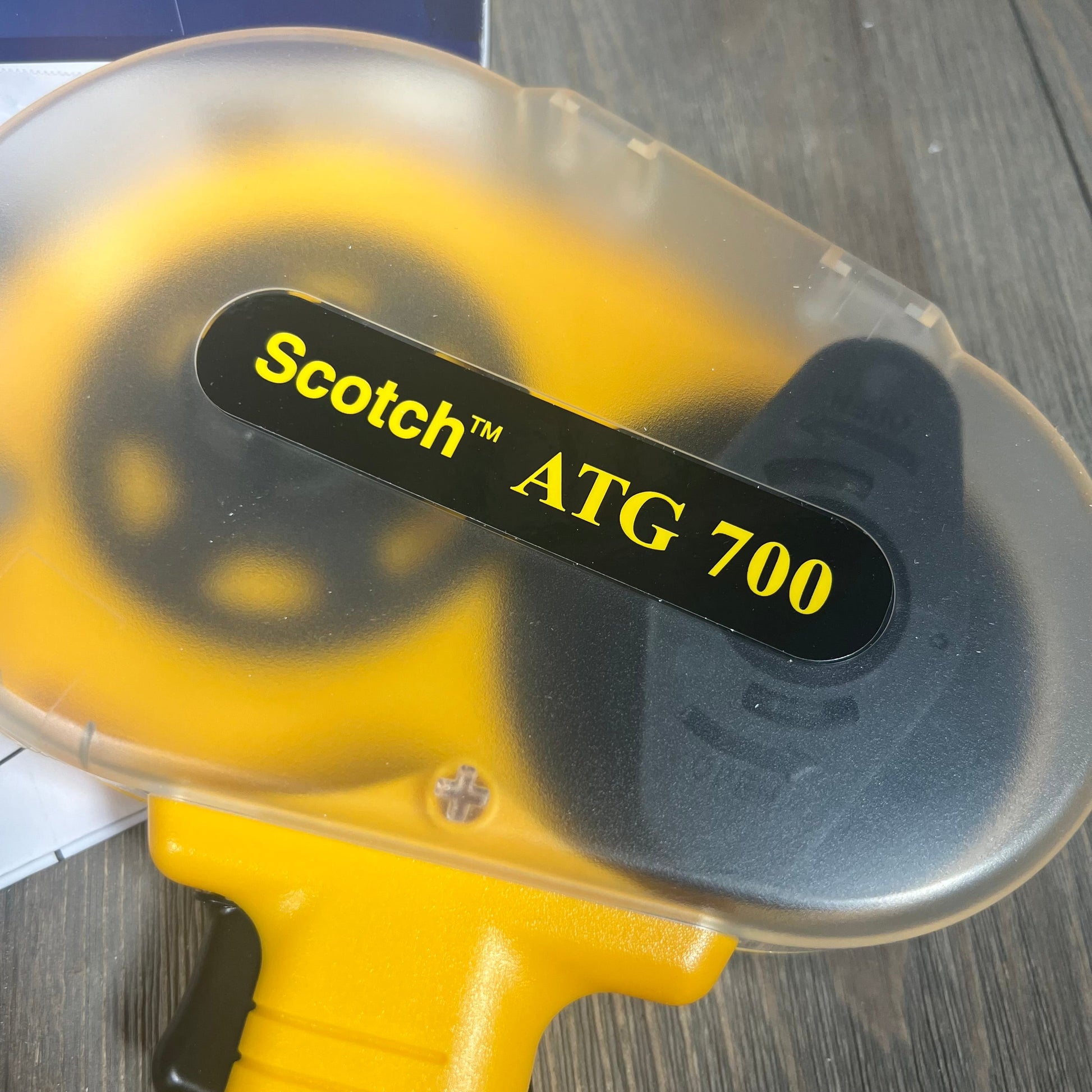 Close-up of 3M Scotch ATG 700 Adhesive Applicator, showcasing its yellow design for 1/2 in and 3/4 in rolls.