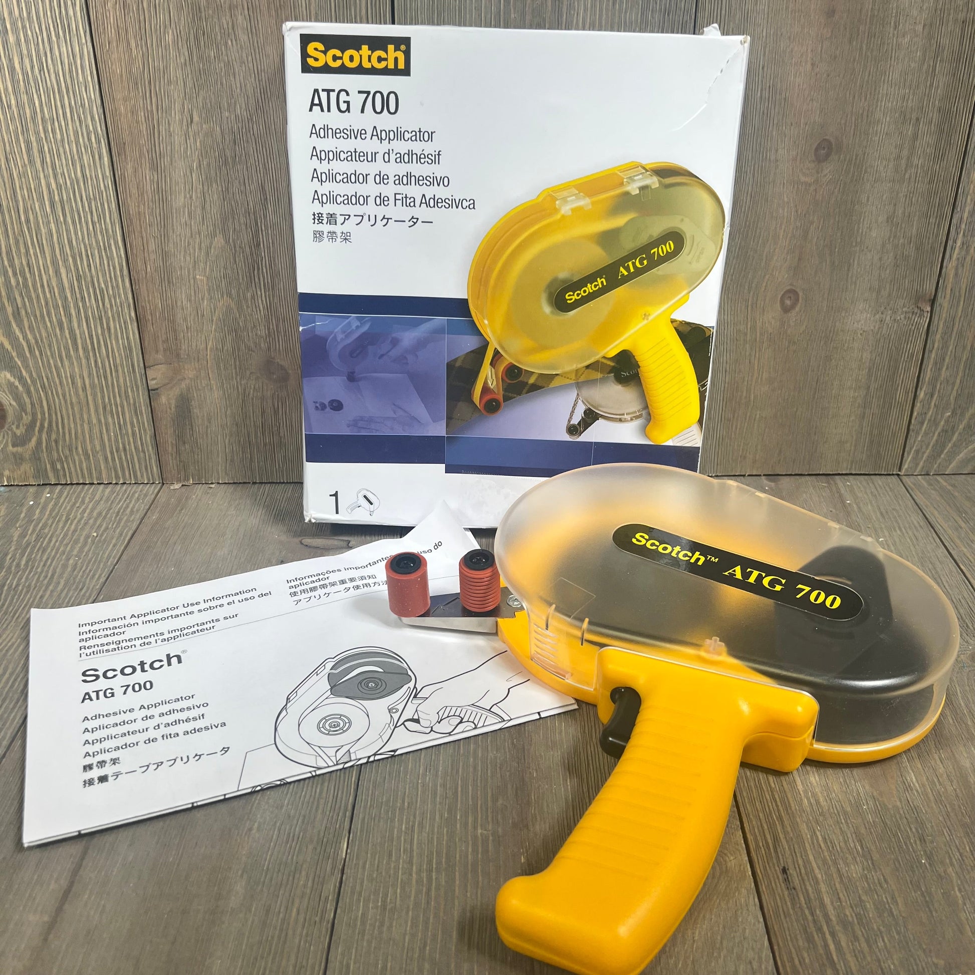 Yellow 3M Scotch ATG 700 Adhesive Applicator with packaging and instructions, fits 1/2 in and 3/4 in wide rolls.