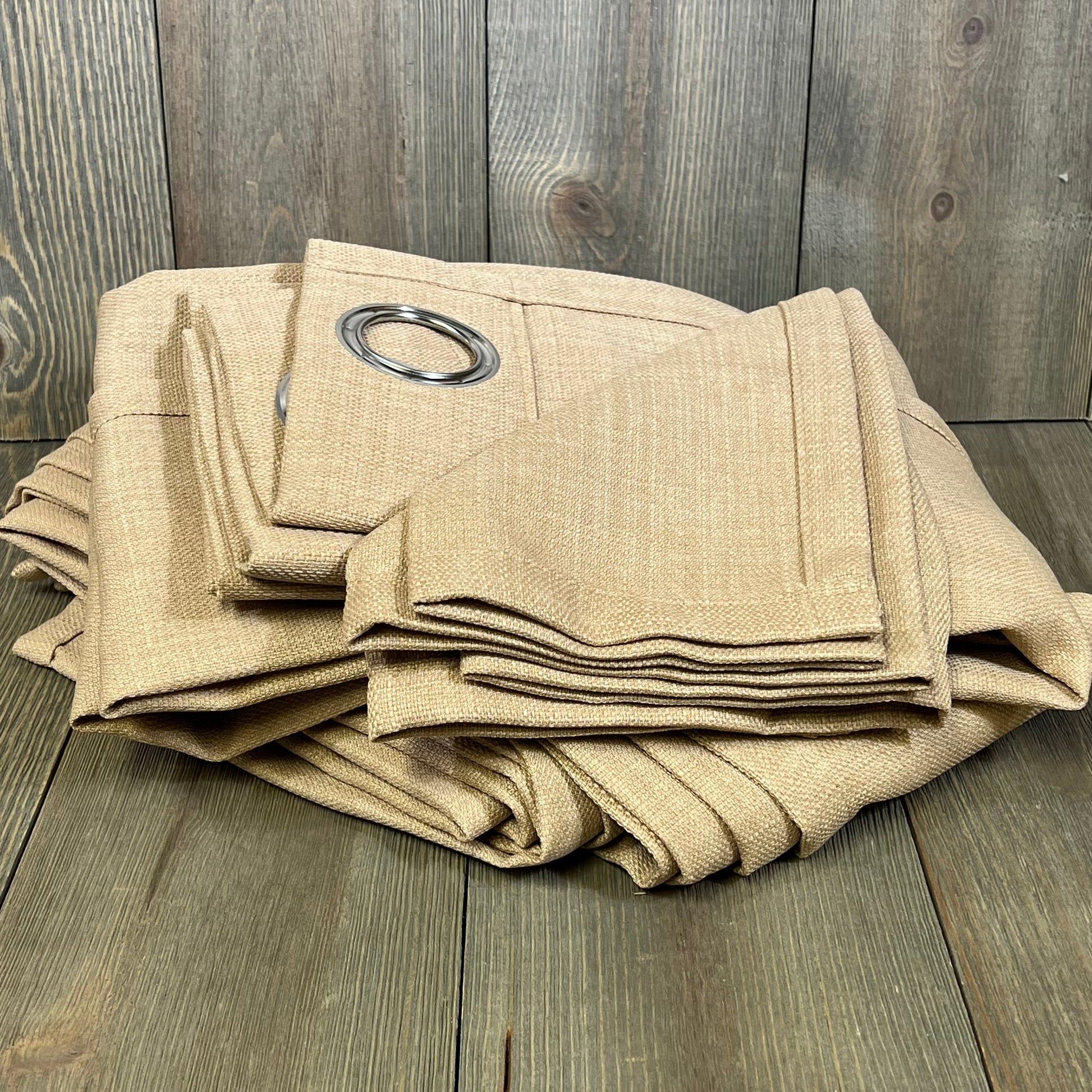Tan faux linen curtains with burlap texture, folded neatly, showcasing grommet detail for living room privacy.