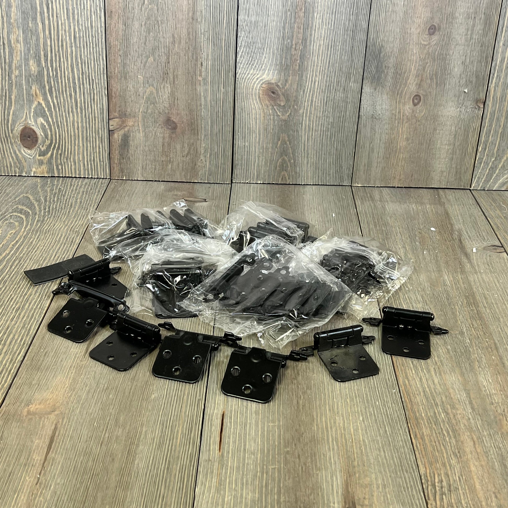 Black 1/2 inch overlay cabinet door hinges, 30 pack, arranged on a wooden surface, ideal for kitchen cupboards.