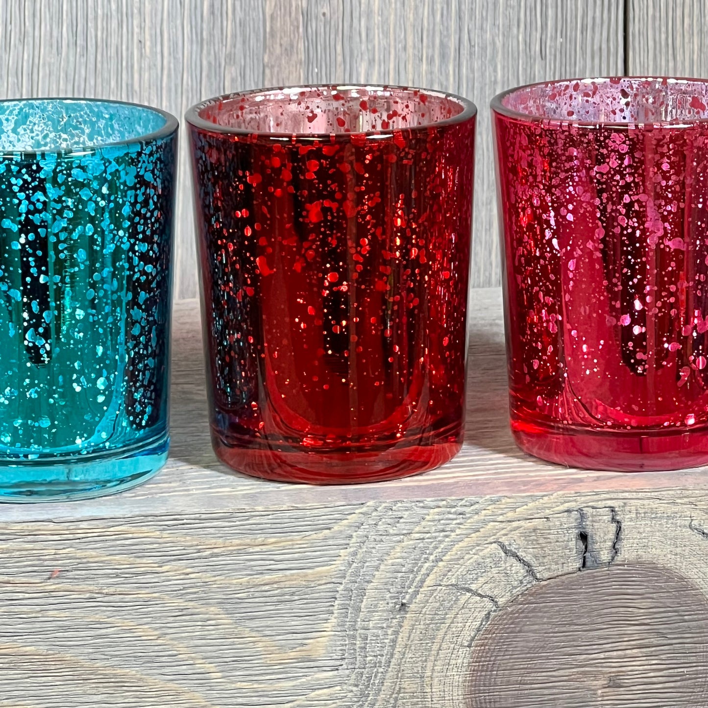 Colorful jewel tone mercury glass votive candle holders in deep blue, red, and pink, perfect for elegant decor.
