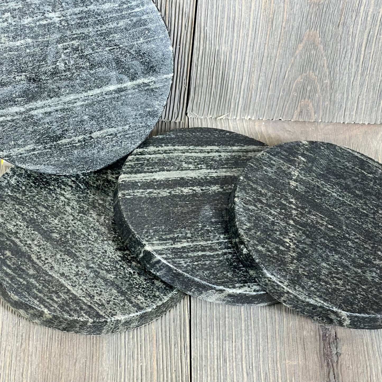 Natural black marble coasters in a 4-pack, showcasing elegant design and heat resistance on a wooden surface.