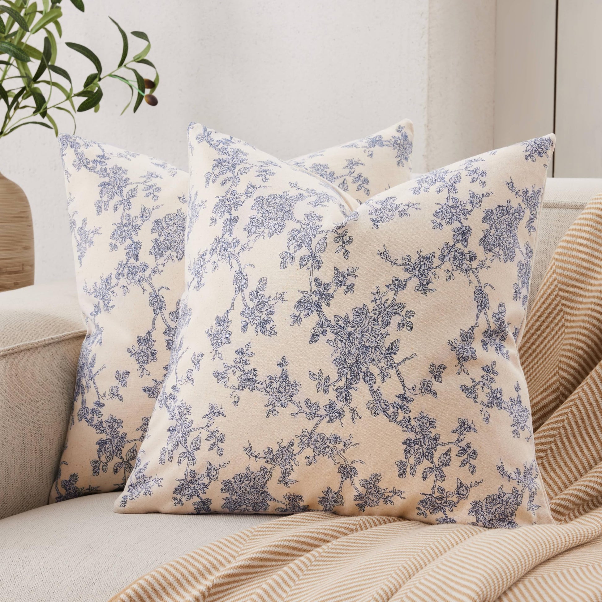 Blue floral cotton throw pillow covers on a beige sofa, adding a farmhouse charm to living room decor.