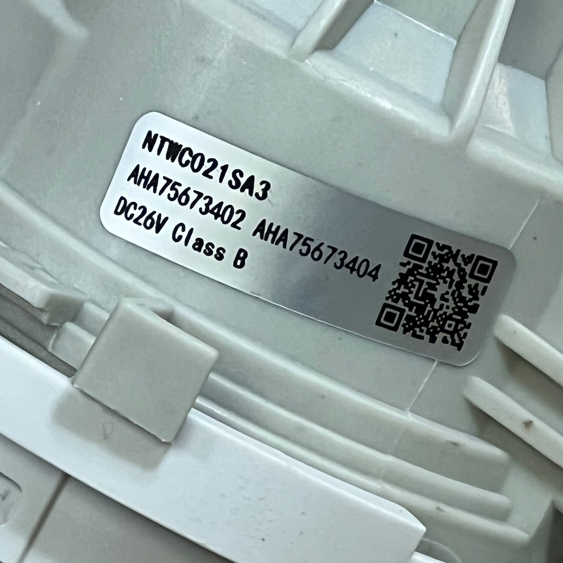 Close-up of 1045801872-AHA75673404 LG washer drain pump assembly, showing model number and QR code for easy identification.