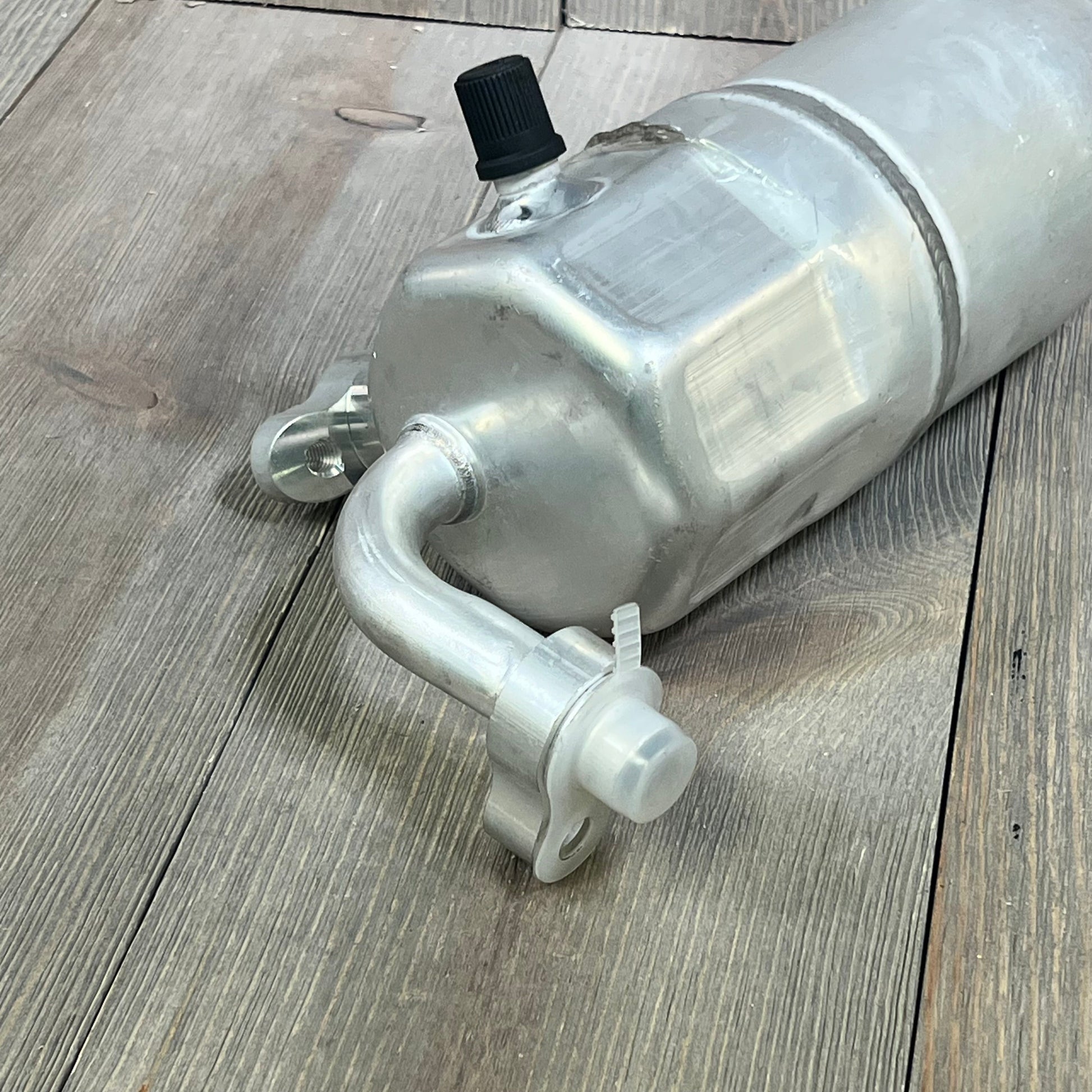 Universal Air Conditioner RD 1801C A/C Accumulator, silver metal finish, resting on wooden surface.