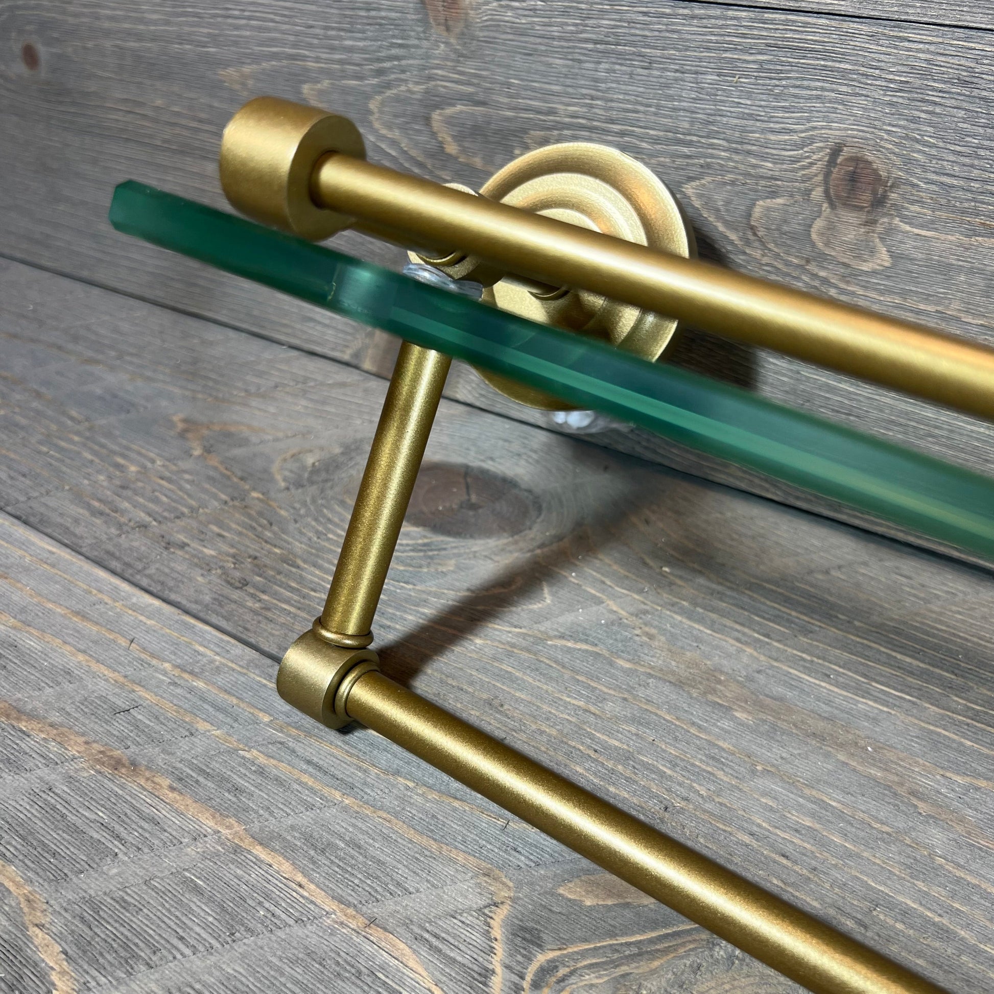 Sleek brass paper towel holder with 22-inch glass shelf, mounted on rustic wood background.