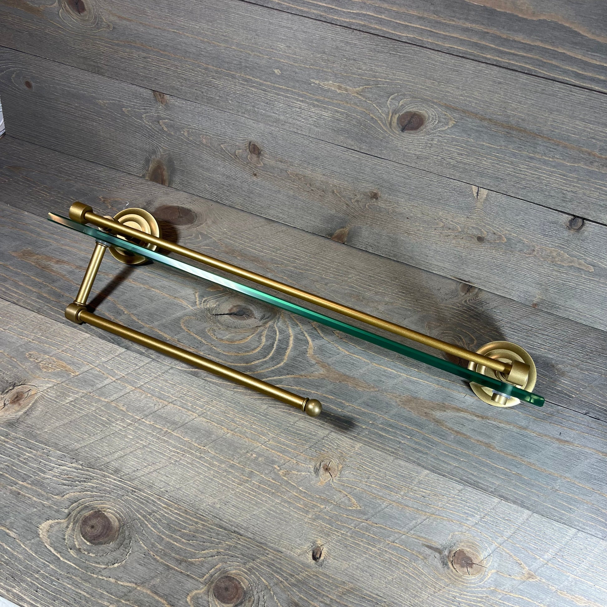 Sleek brass paper towel holder with a 22" glass shelf, ideal for modern kitchens or bathrooms.