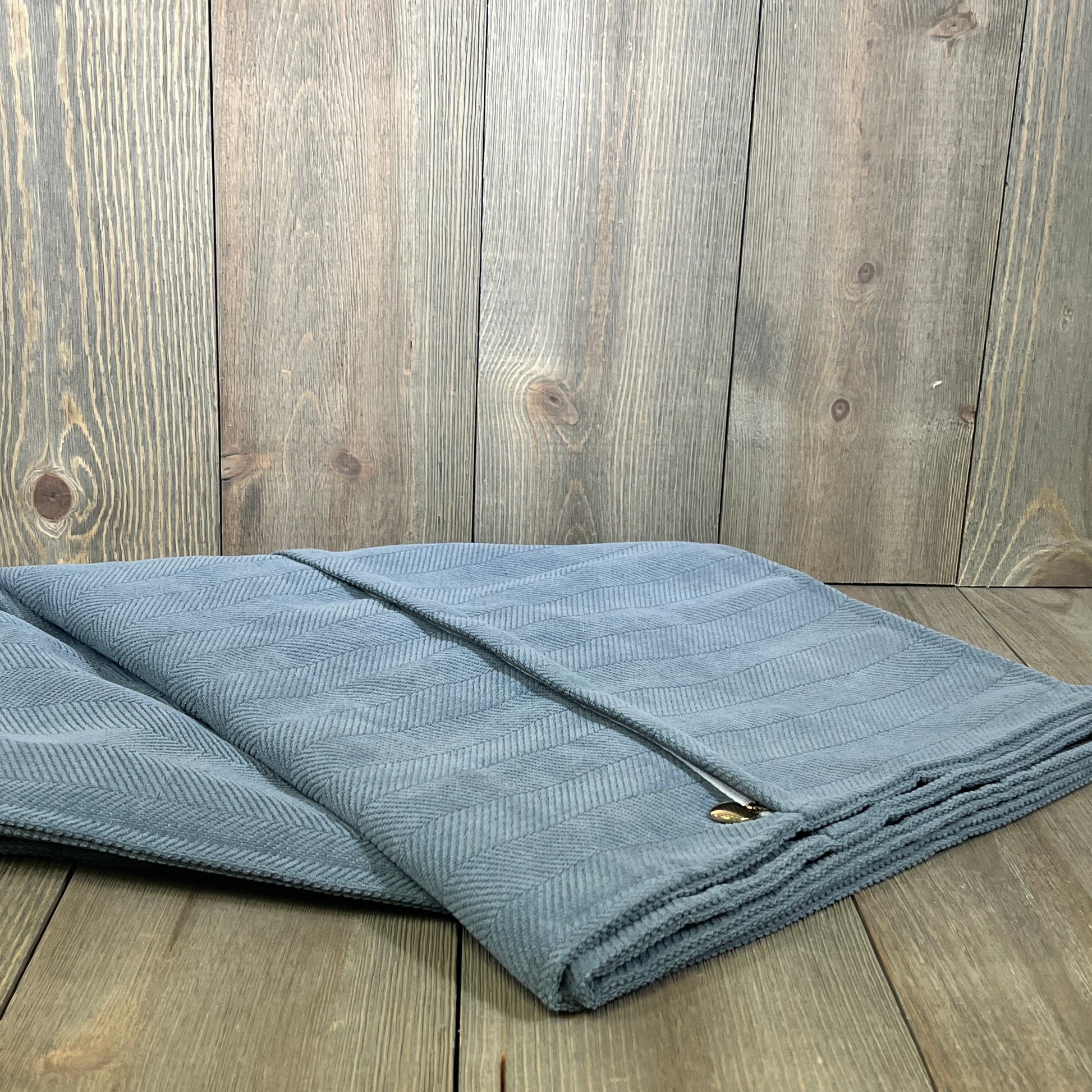 Dusty blue chenille pillow covers folded on wood, showcasing elegant design and luxurious texture for home decor.