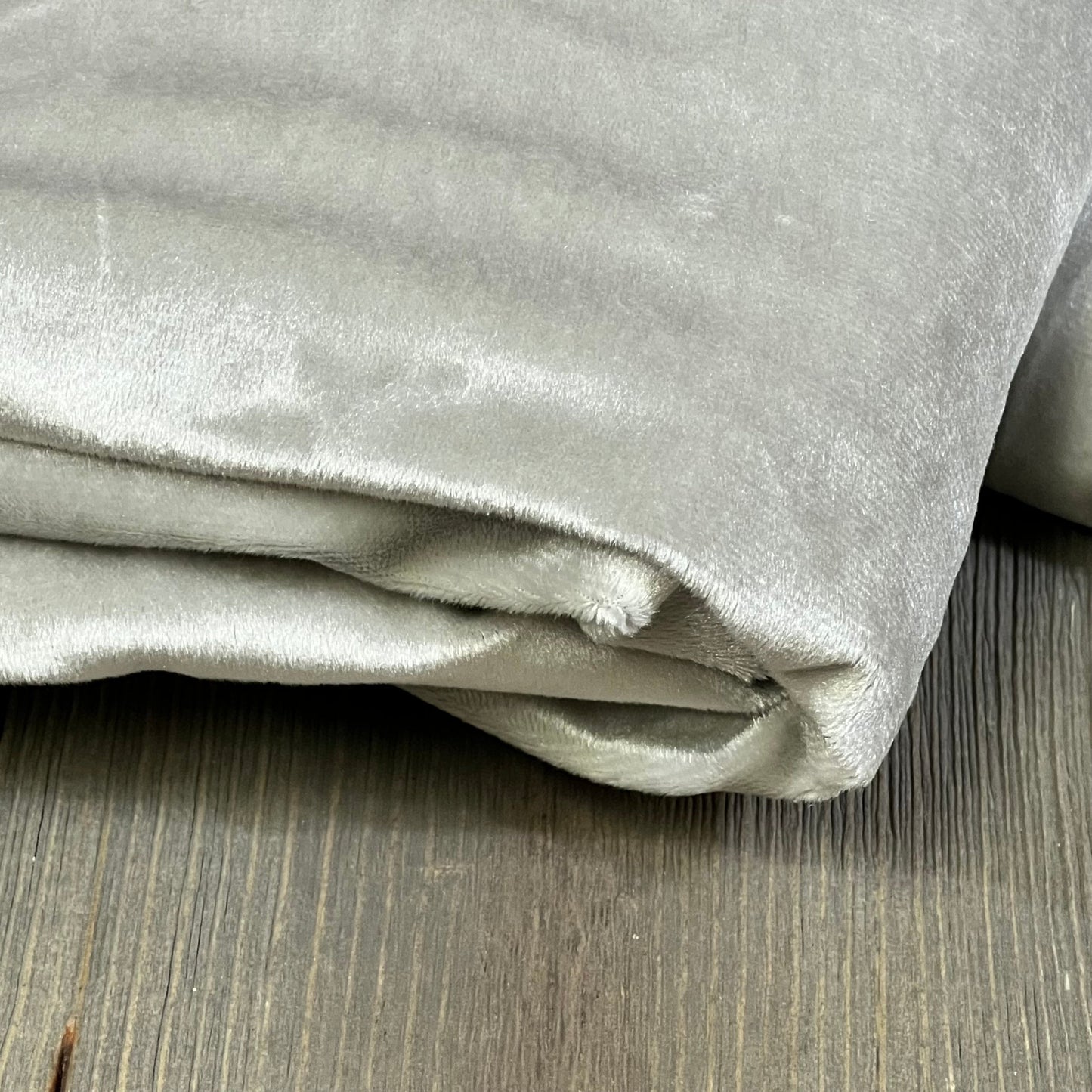 Folded MIULEE grey blackout curtain on wooden floor, showcasing soft fabric and thermal insulation for living room or bedroom.
