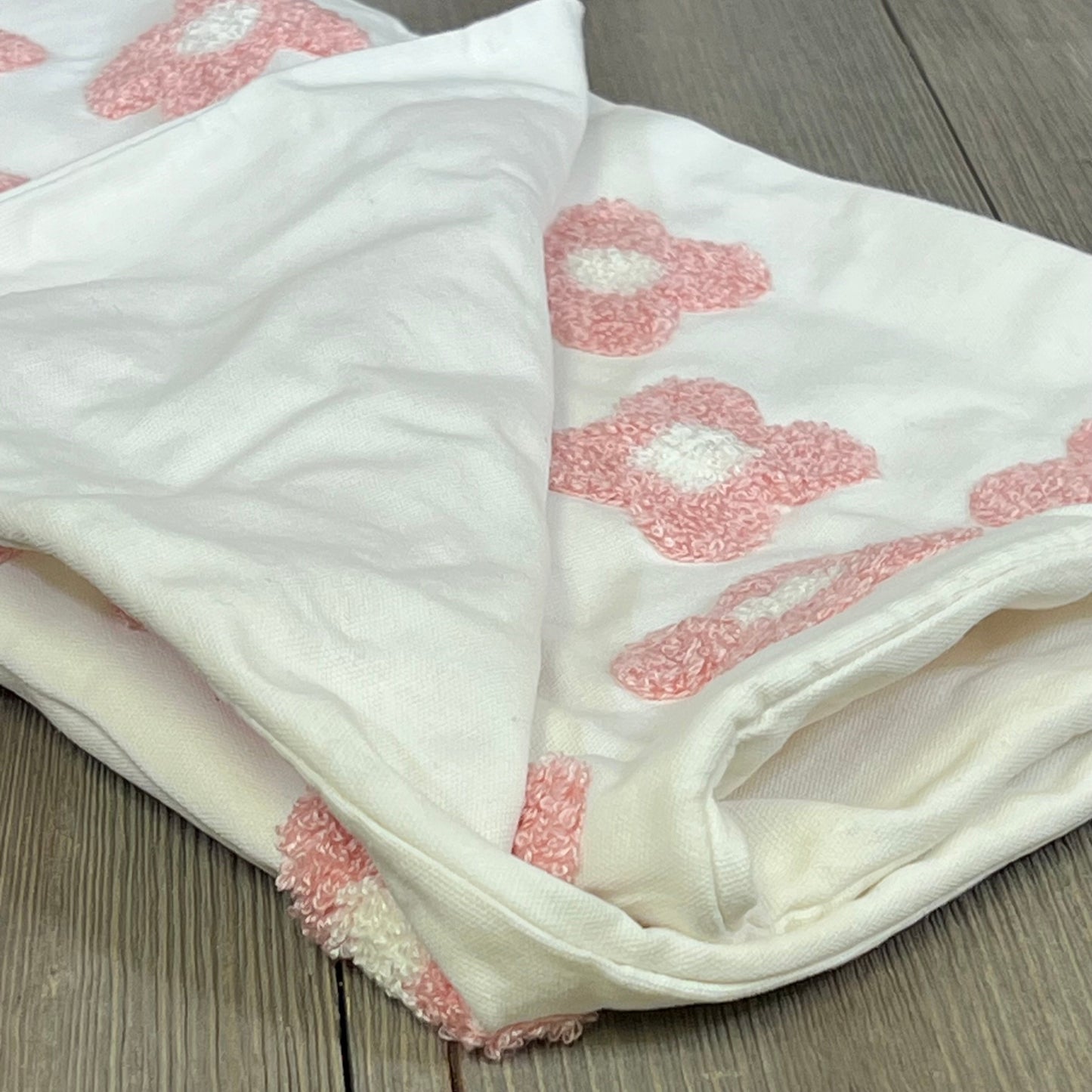Pink and white daisy sun flower jacquard pillow cover, folded on a wooden surface, perfect for couches and beds.
