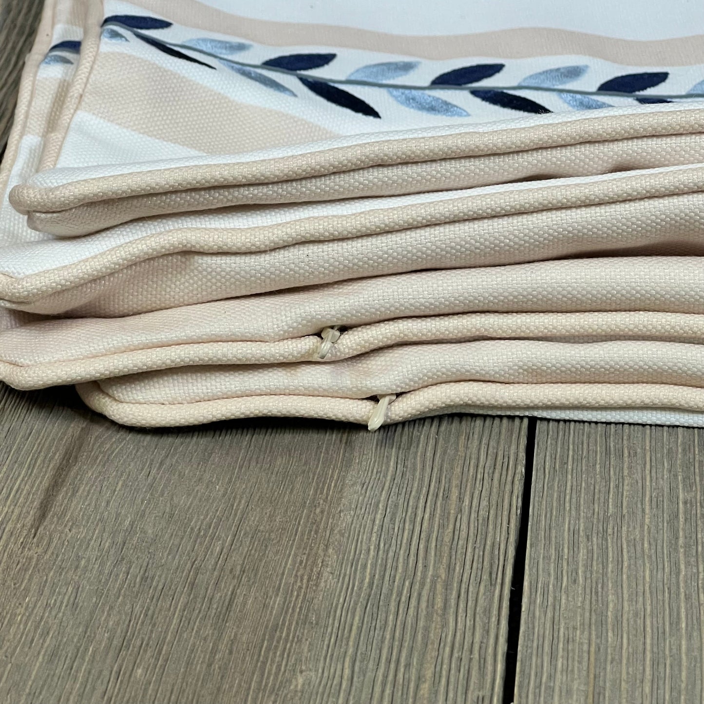 Neutral tan lumbar pillow cover with embroidered leaf design and piping, perfect for indoor outdoor use.