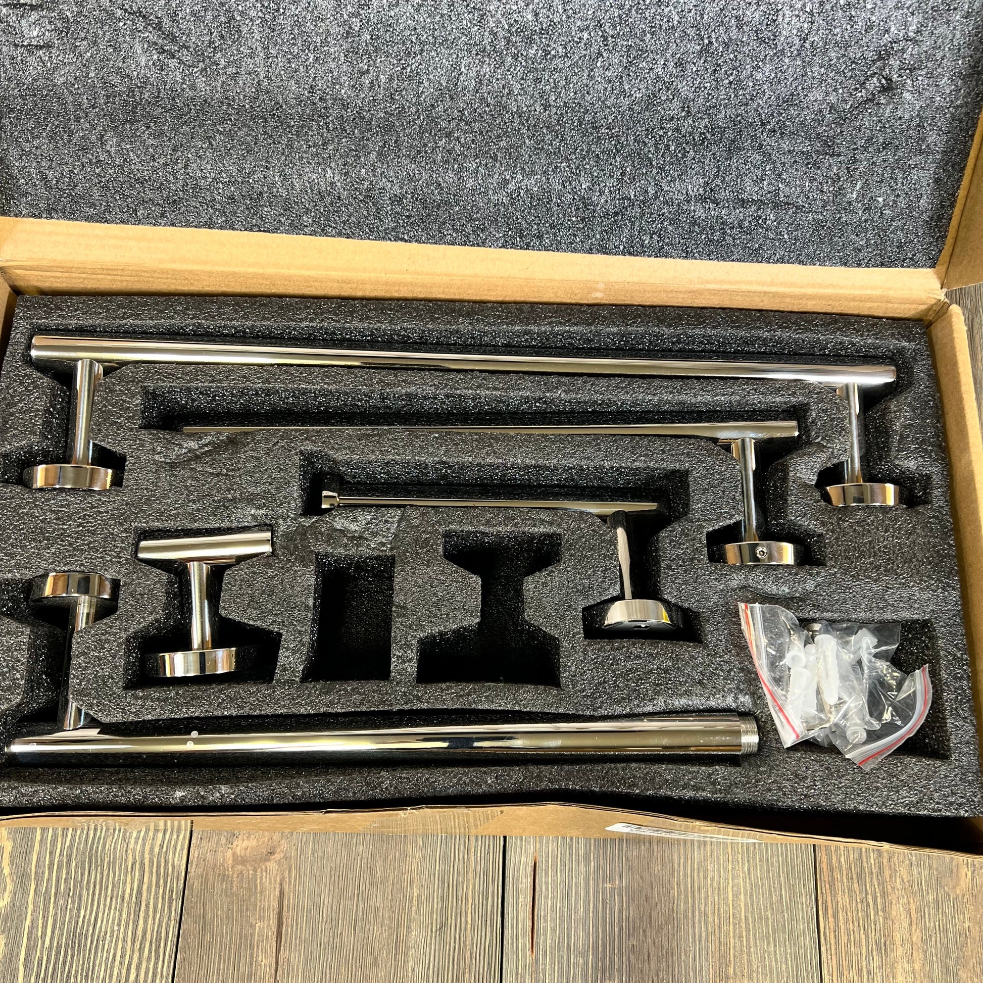 Bathroom hardware set in polished chrome, featuring stainless steel towel bars and accessories in foam packaging.