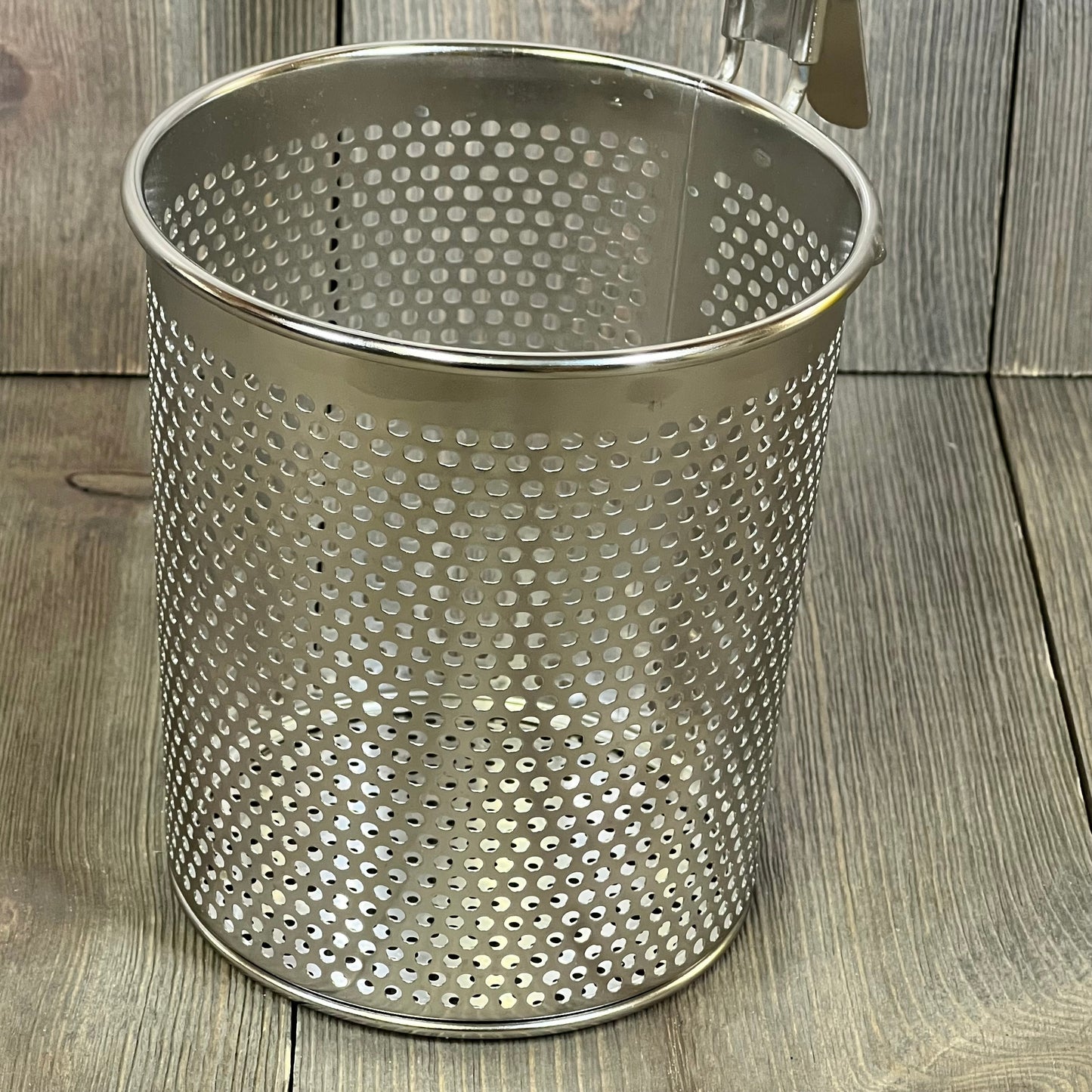Stainless steel pasta cooker basket with perforated design, featuring a sturdy wood handle for easy straining and cooking.