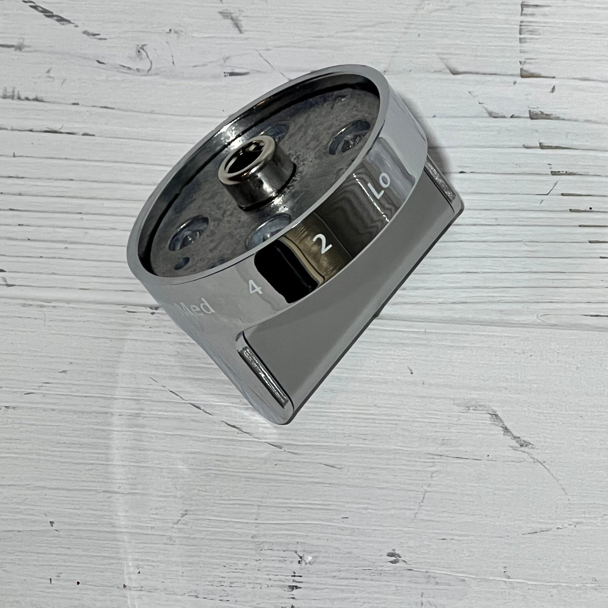 Stainless steel gas stove knob replacement for Whirlpool, showing detailed top view on a textured white surface.
