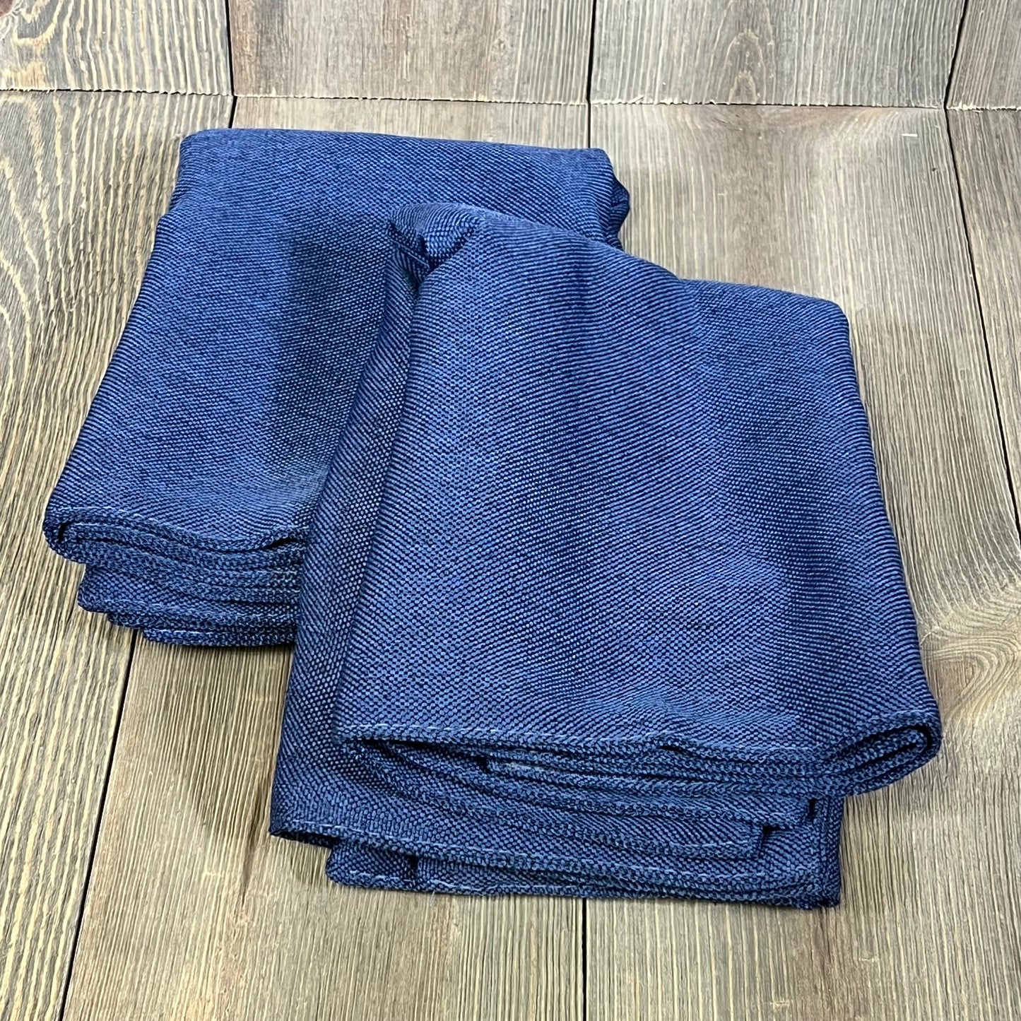 Dark blue waterproof linen pillow covers folded on wooden surface, perfect for outdoor patio furniture and modern living rooms.