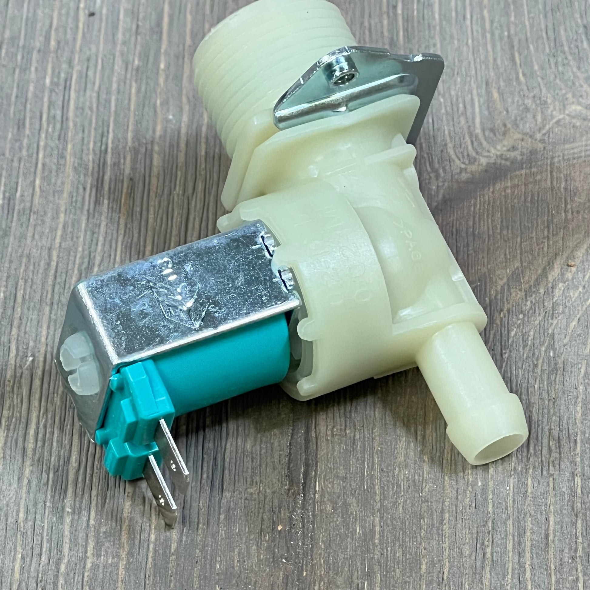 White and teal water inlet valve for LG, Kenmore washer, model 1045811647-5220FR2075L, shown on wood surface.