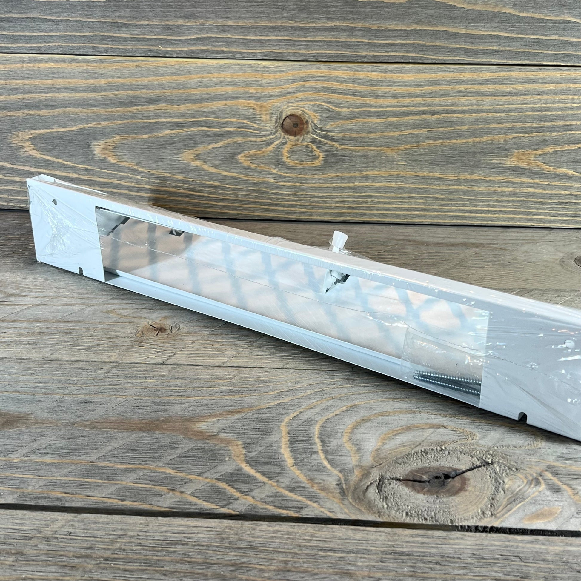 White 18-inch baseboard vent cover with a modern design for home floors and walls, includes screws for easy installation.