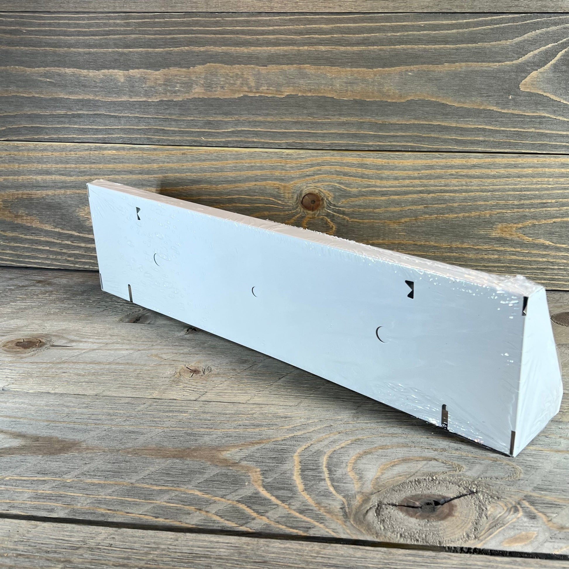 White 18-inch baseboard vent cover with modern design, shown on wooden surface, ideal for home air distribution.