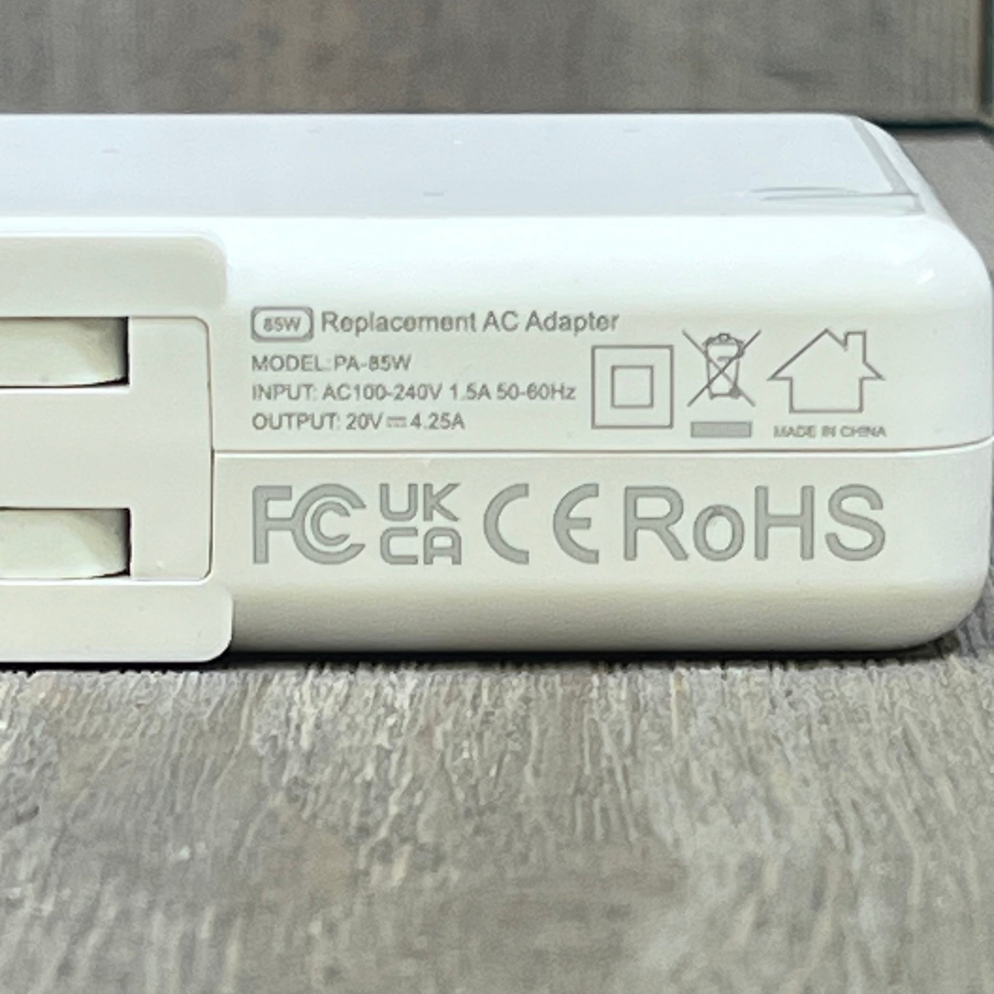 Close-up of 140W MacBook Pro charger showing specifications and certification logos on the side panel.