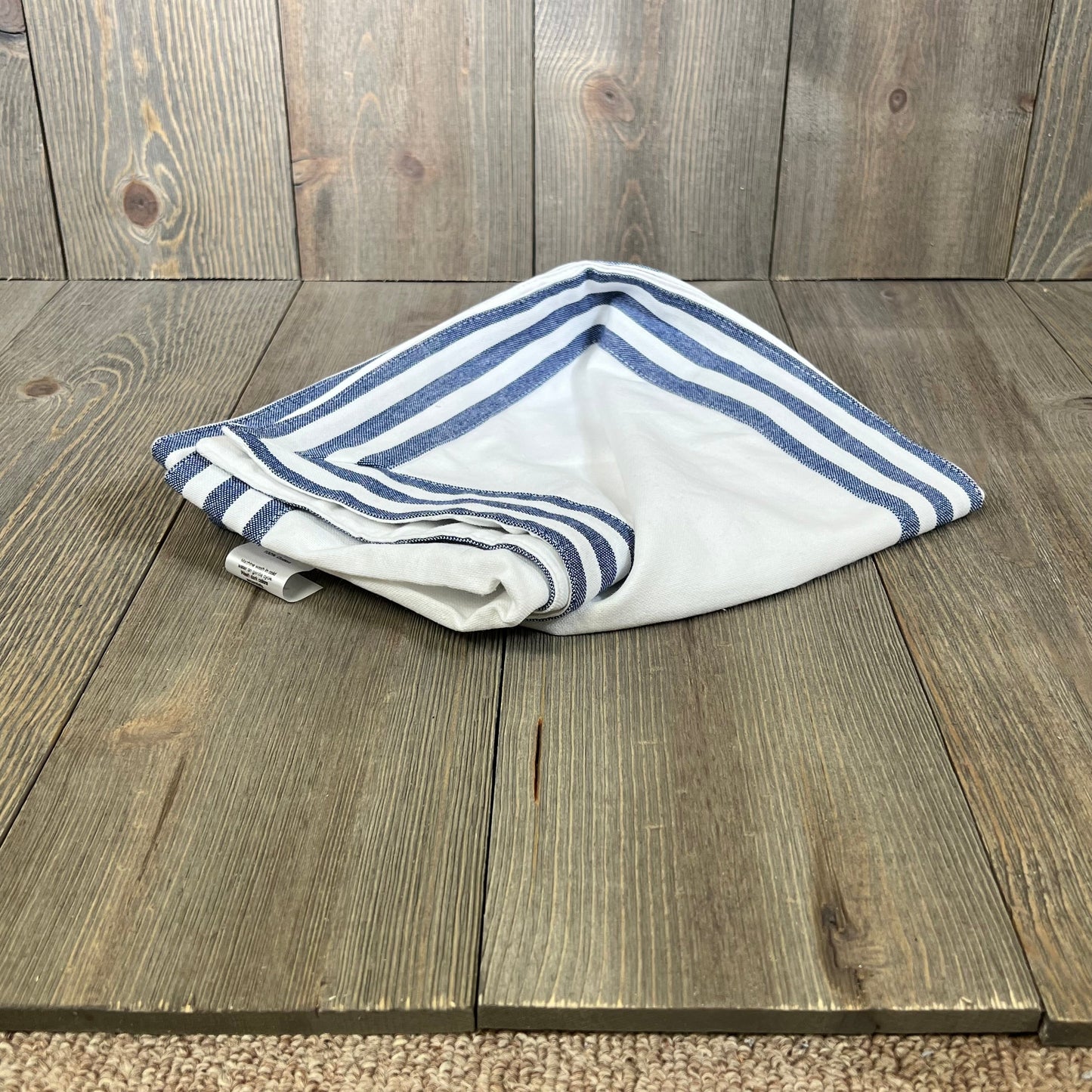 Folded PurpleEssences table runner in white with blue stripe edges, crafted from 100% cotton for durability.