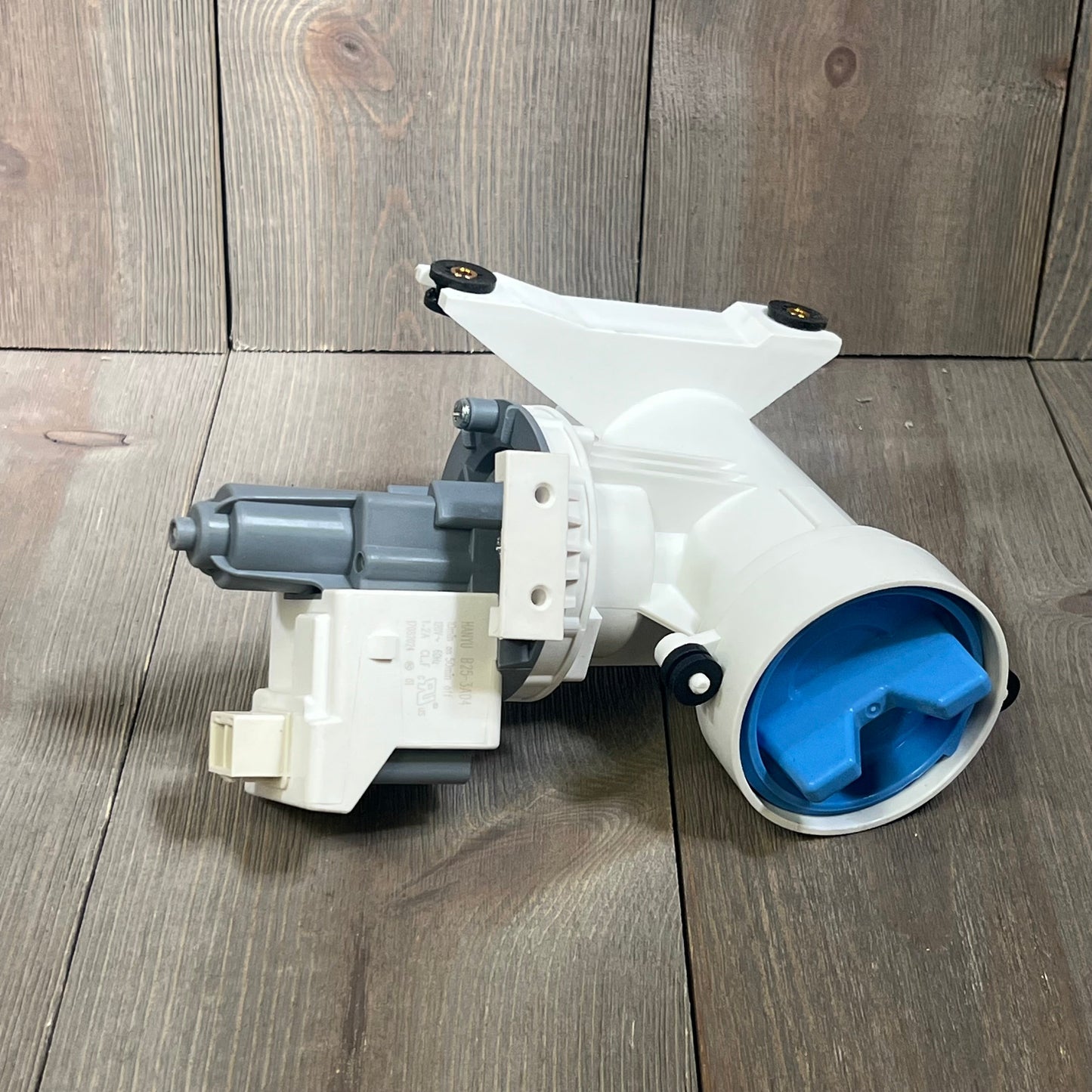 Washer drain pump and filter for GE washing machines, model WH11X29539, shown on wooden surface.