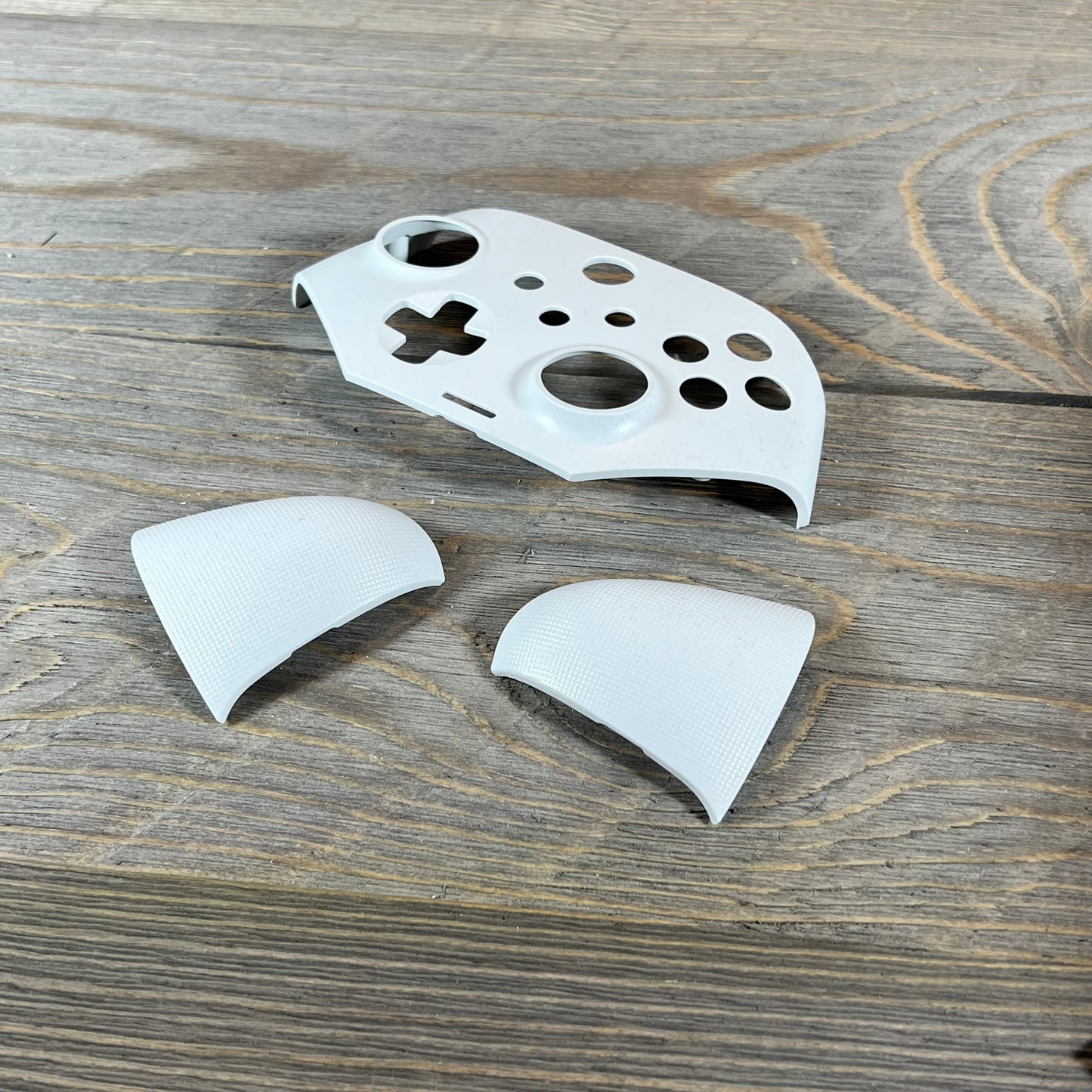 White EasySMX X10 controller shell and grips on wooden surface, showcasing customizability.