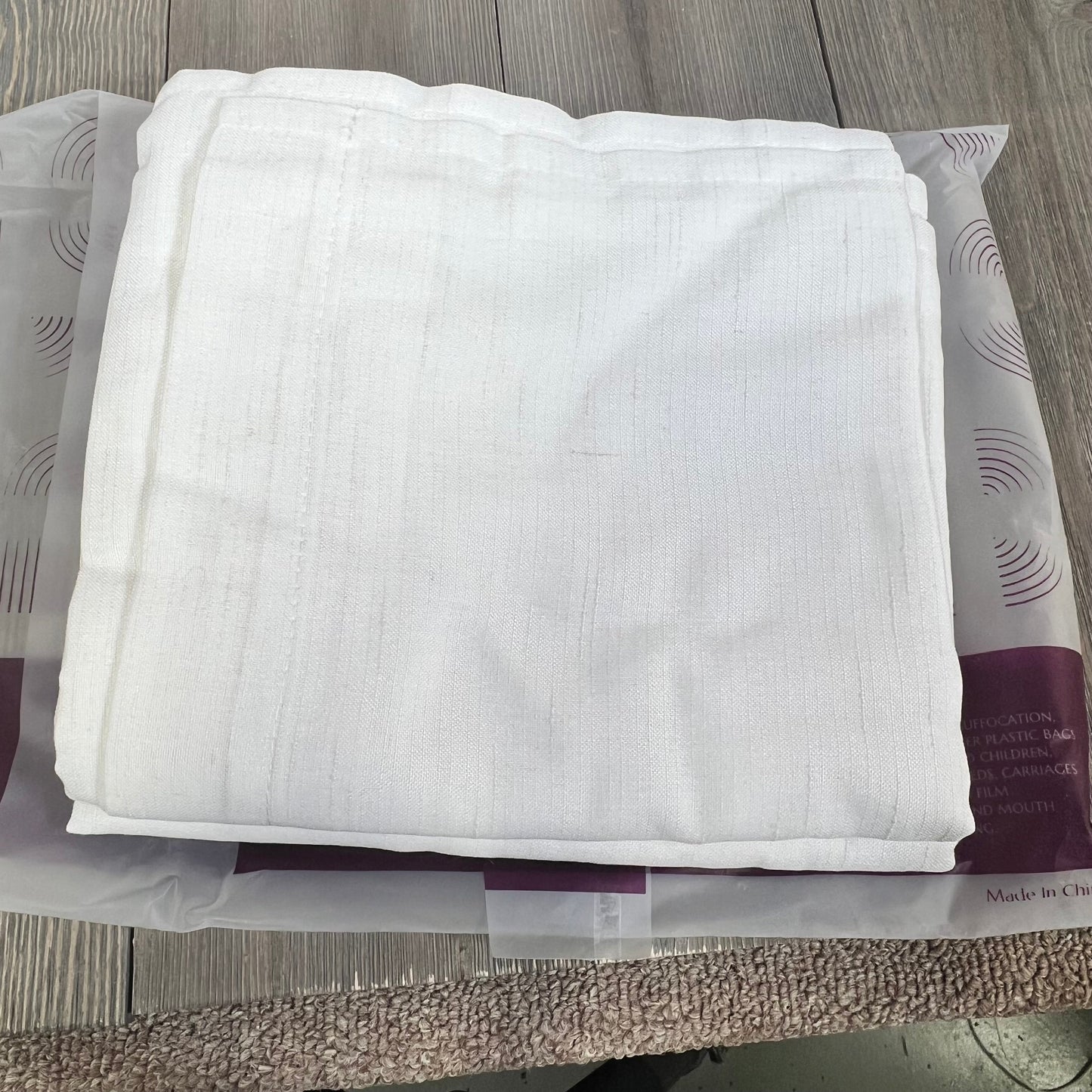 White linen blend curtains folded on a table, showcasing light filtering fabric suitable for farmhouse living rooms.