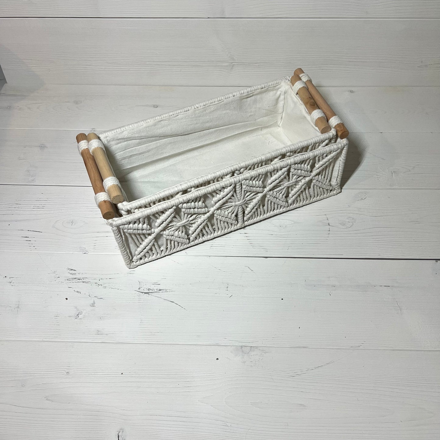 Handwoven macrame storage basket in ivory white with wooden handles, ideal for bathroom or bedroom decor. Bohemian style organizer.