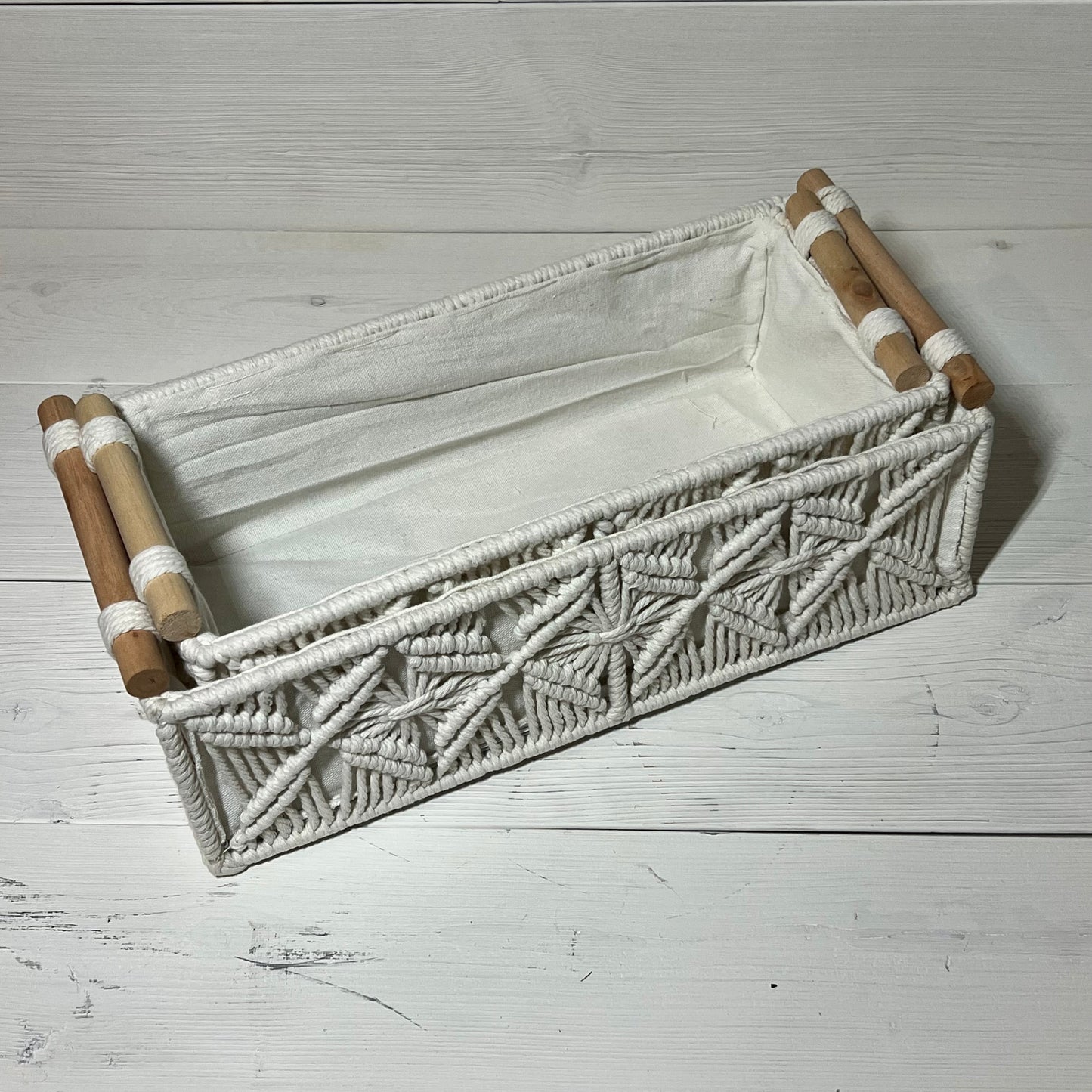 Handwoven ivory macrame storage basket with wooden handles, perfect for organizing bathroom or bedroom essentials.