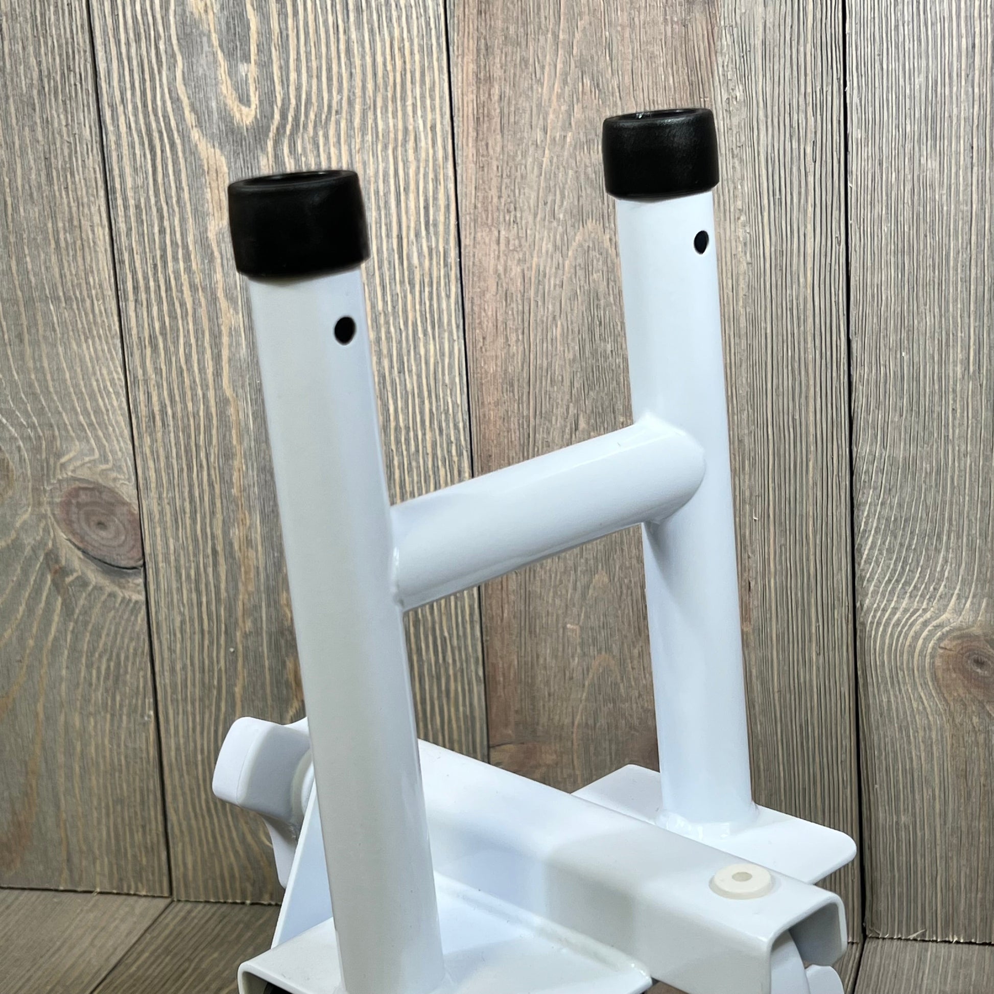 White Vaunn Medical bathtub grab bar with black caps, shown against a wooden background, ideal for senior safety.