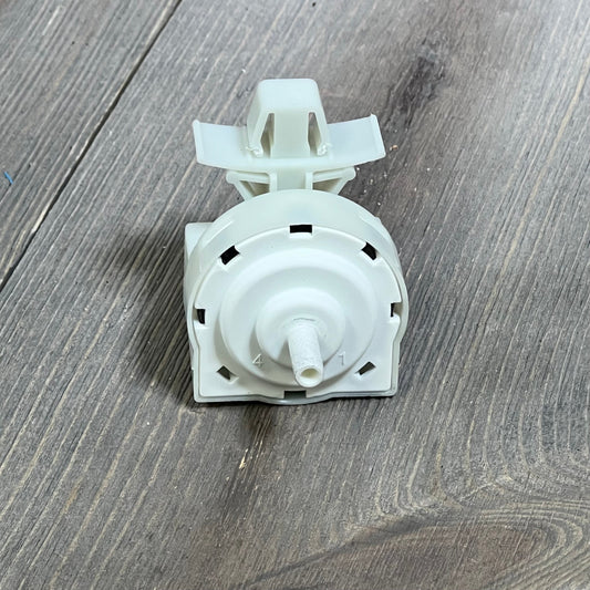 Whirlpool washer pressure switch W11316246 on wooden surface, featuring durable plastic casing and precise water level control.