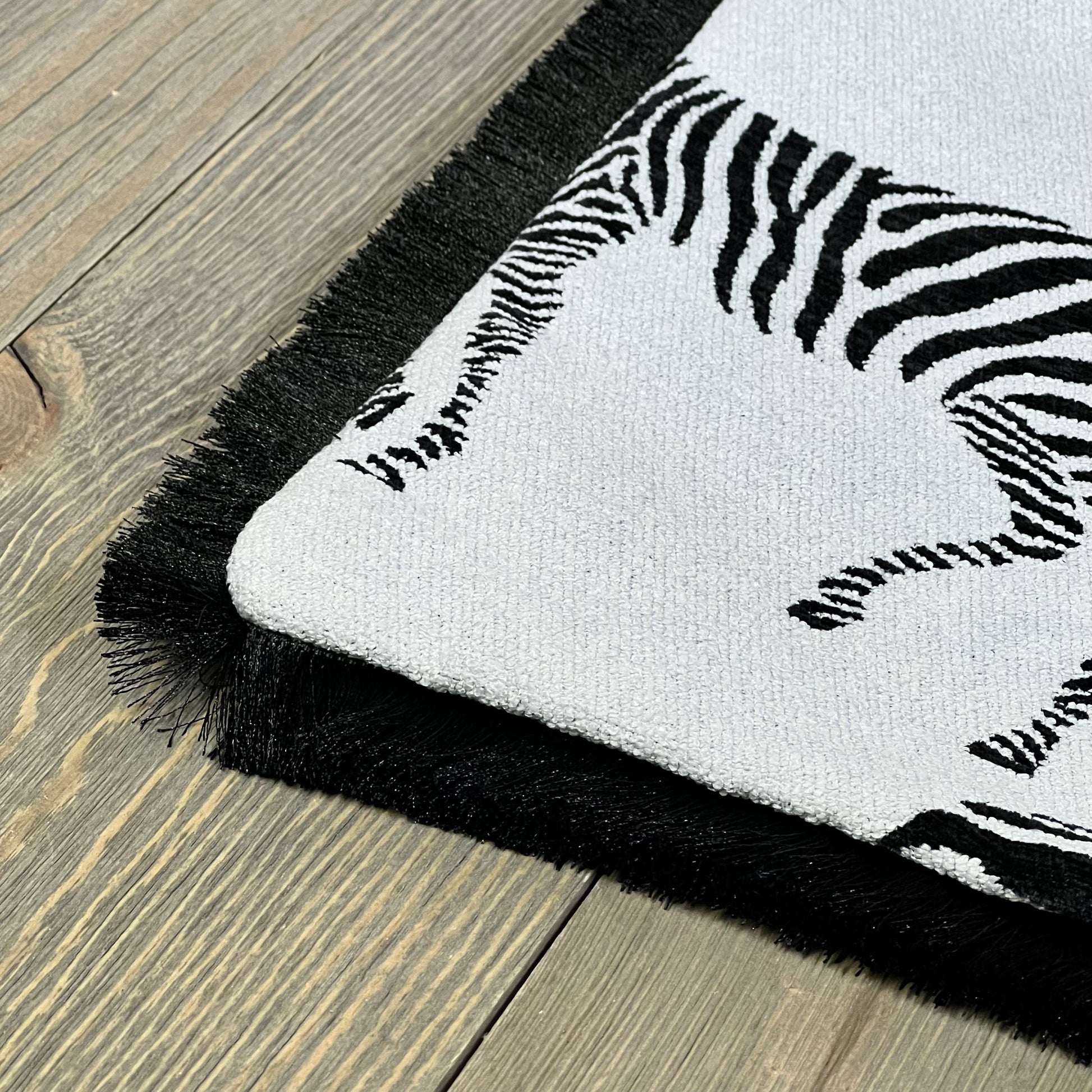 Luxury zebra pattern embroidery on Croker Horse throw pillow cover, featuring elegant black fringe on a wooden surface.