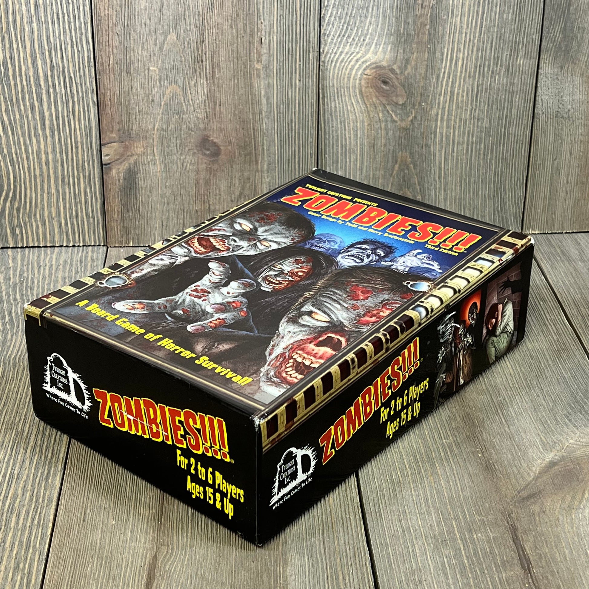Zombie-themed board game box, featuring detailed artwork, for 2-6 players, ages 15+, Twilight Creations' Zombies Third Edition.